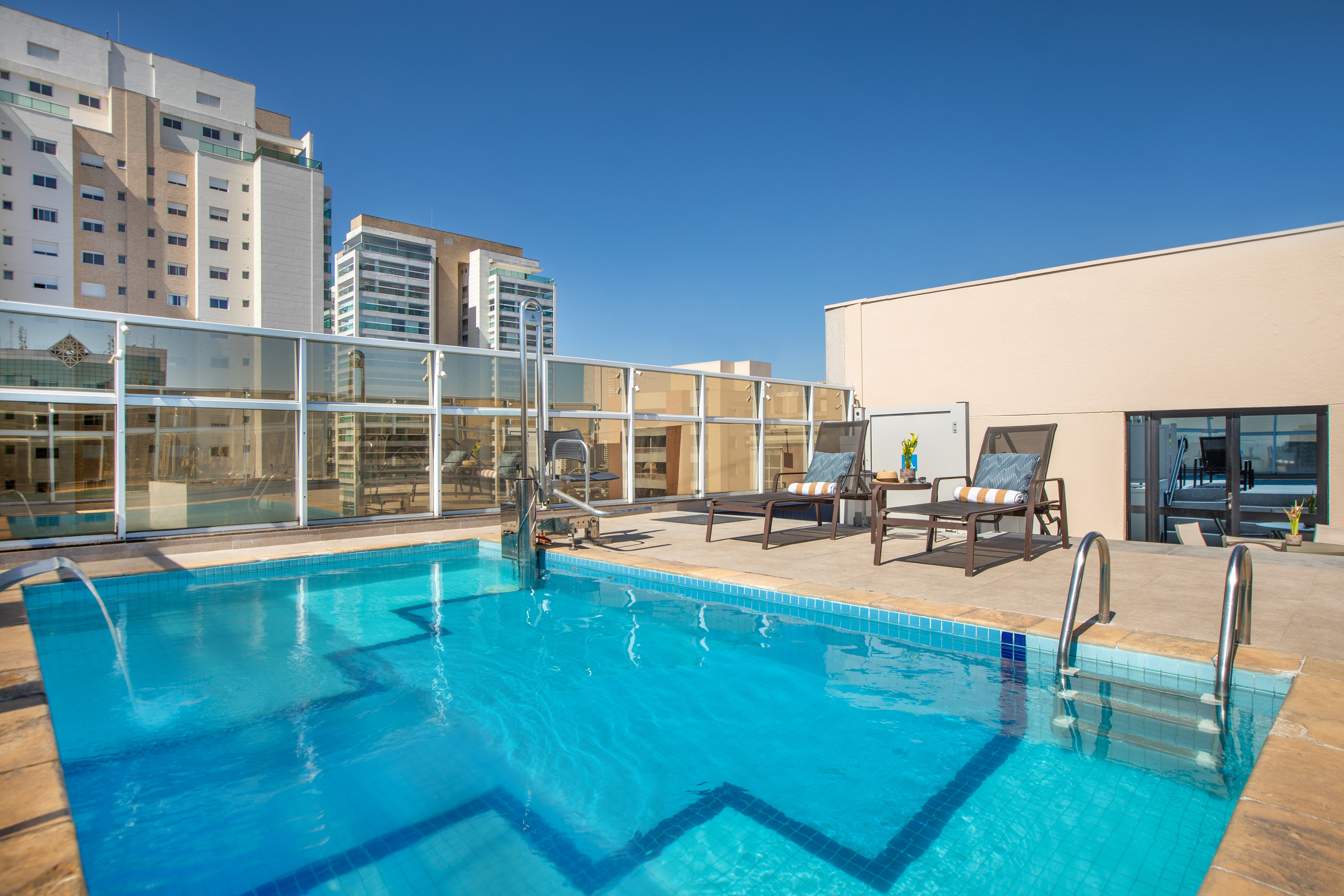 Urban rooftop pool with lounge seating and city skyline view.