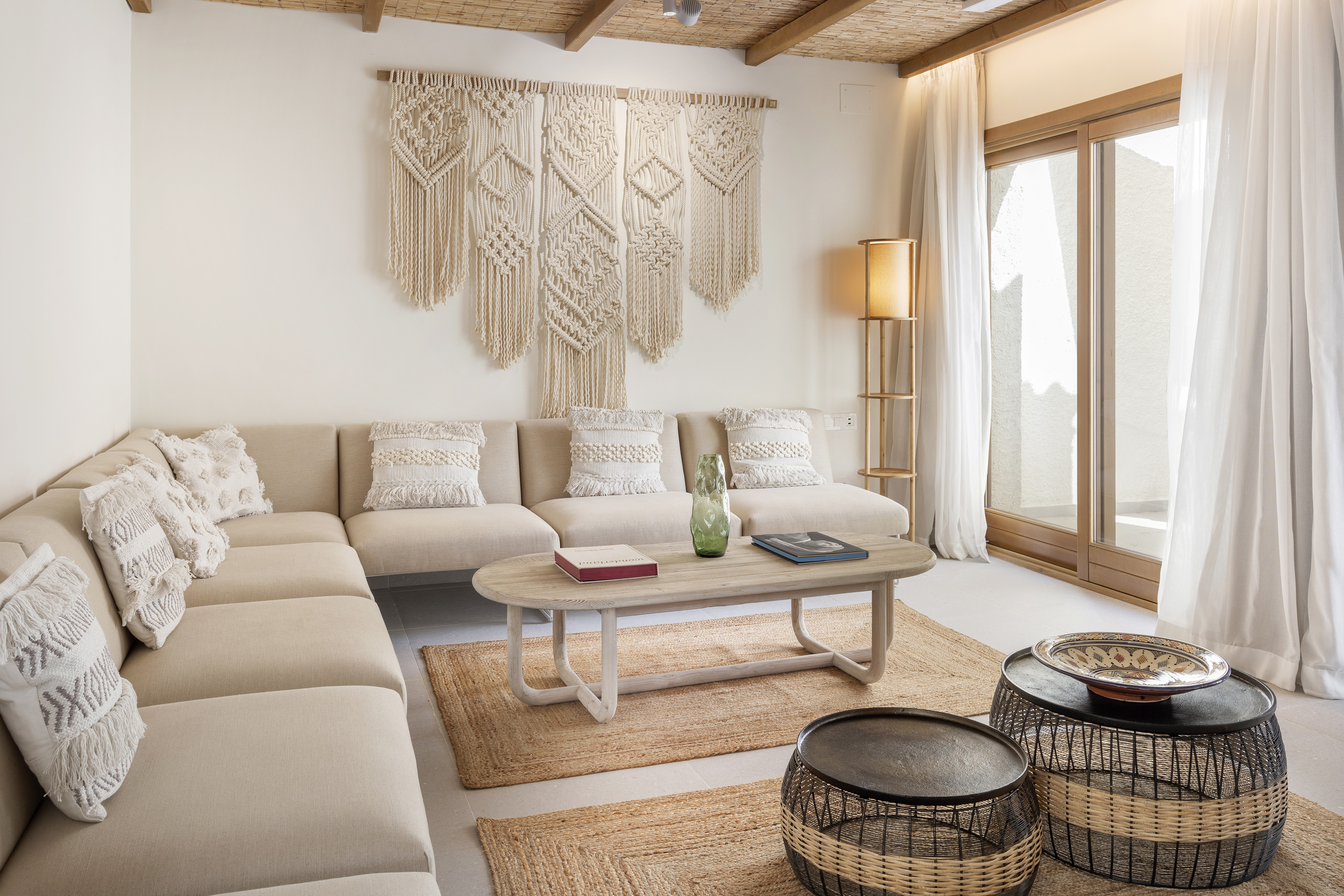 Boho-chic living room with beige sofa, large macrame wall hanging, and woven rug.