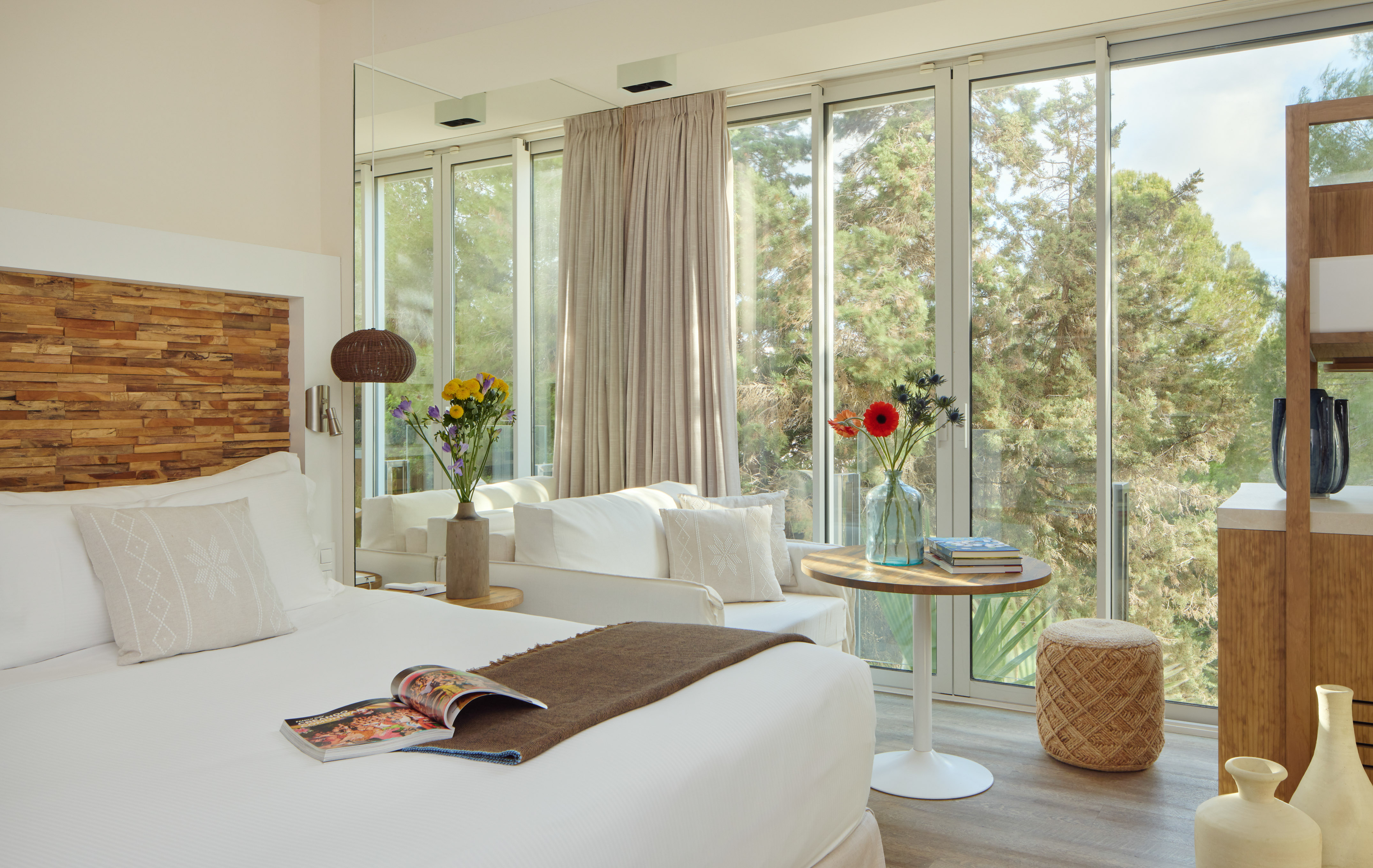 Bright hotel room with large windows, lush tree view, and modern interior.