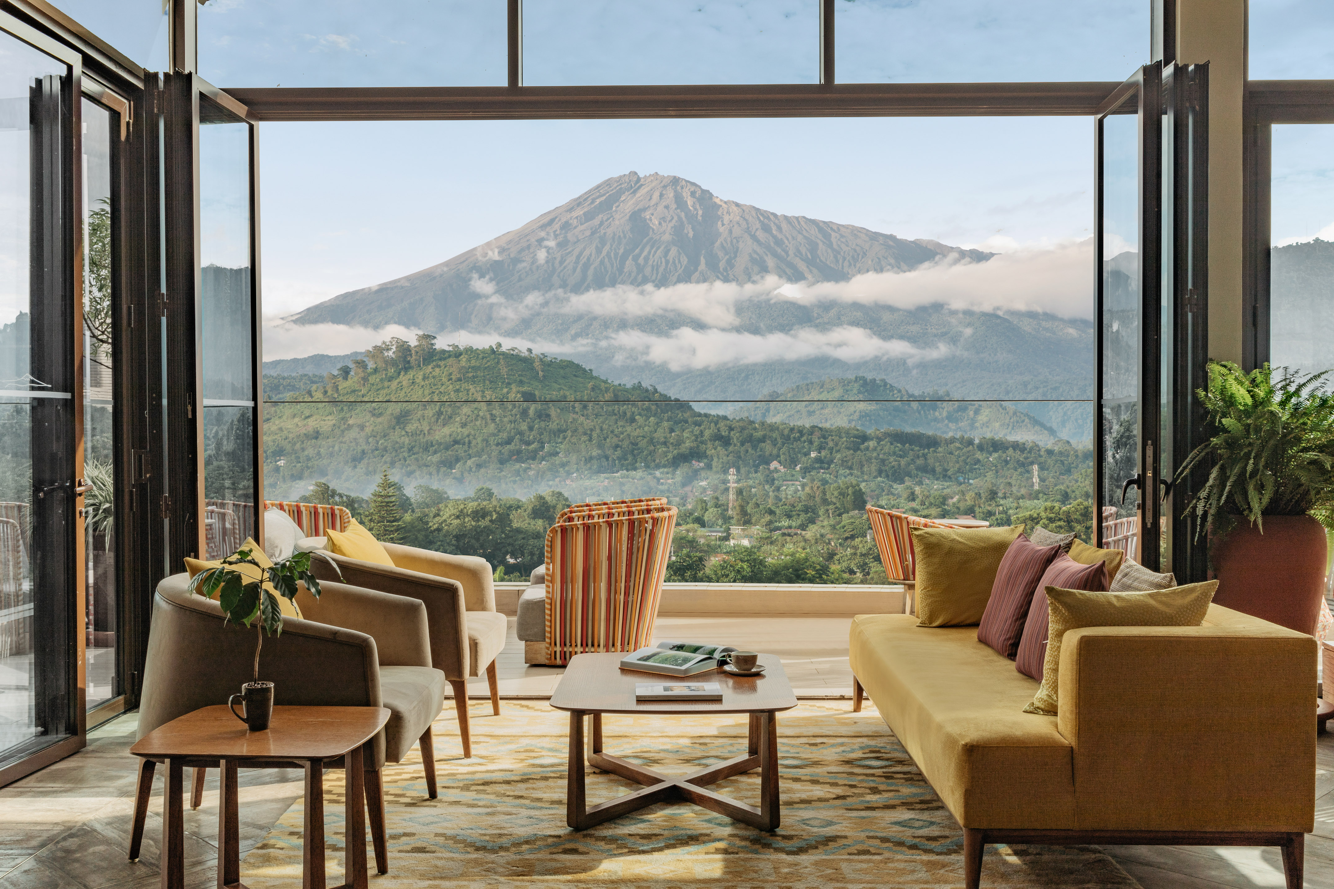 Modern living room with panoramic volcano view and lush landscape.