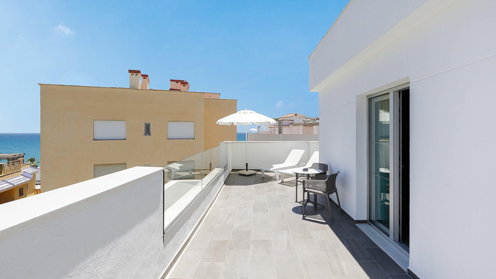 a patio with chairs and umbrella on a roof