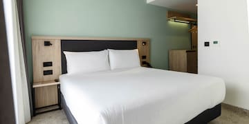 a bed with white sheets and a wood headboard