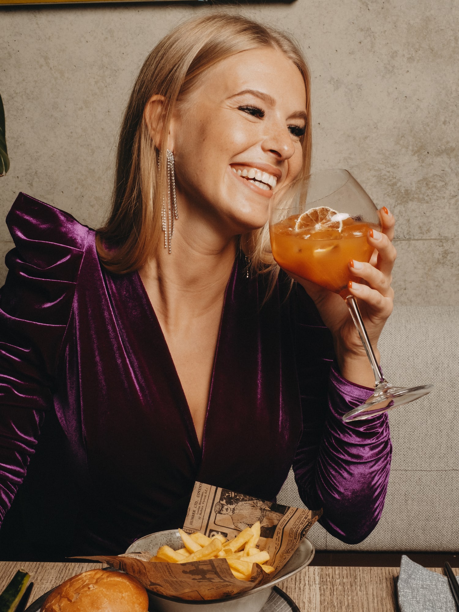 a woman smiling while holding a drink