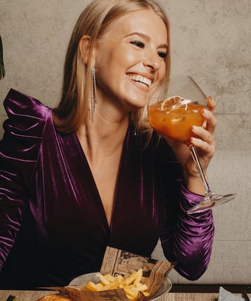a woman smiling while holding a drink