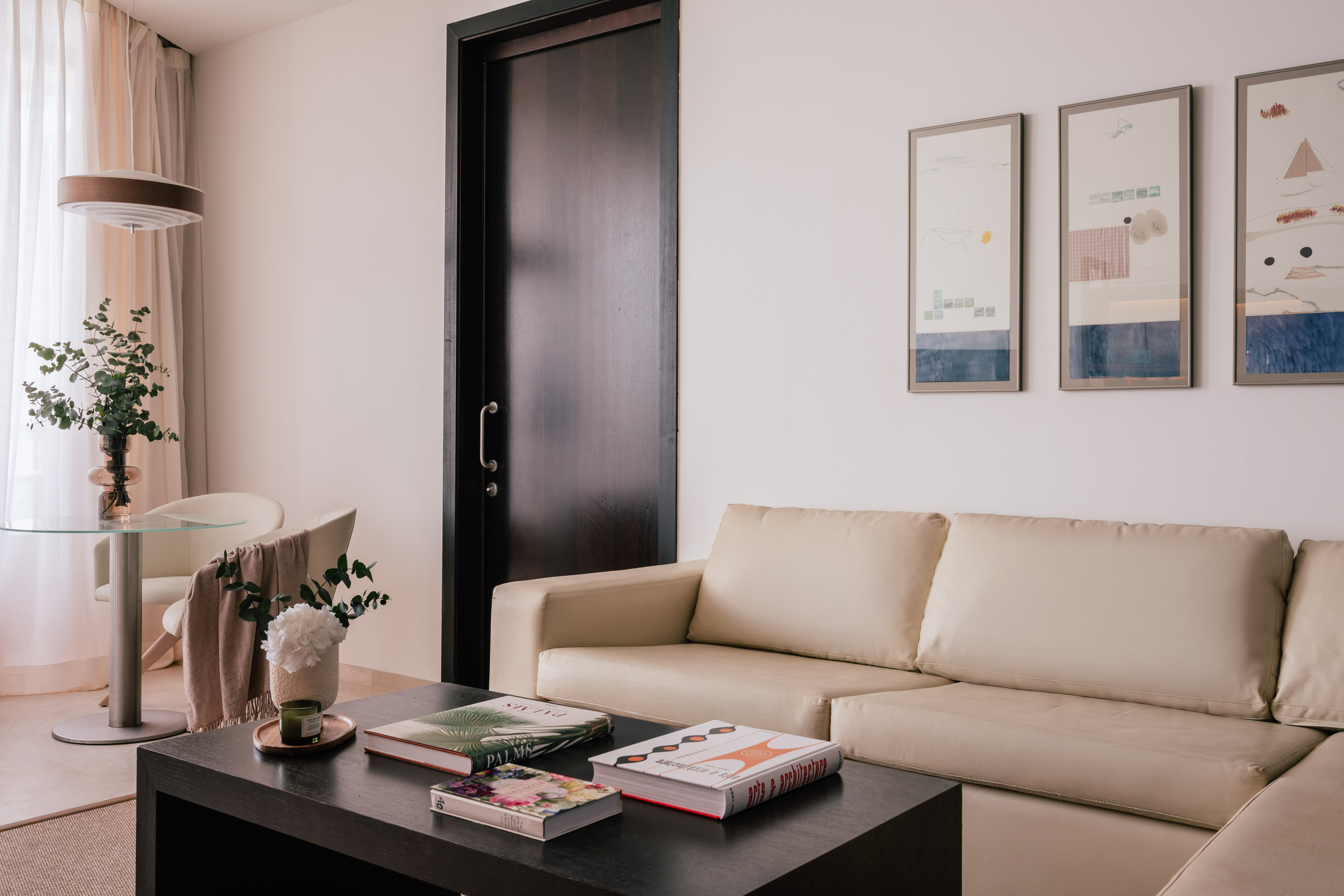 Modern living room: beige sofa, coffee table, abstract art, and dining area.