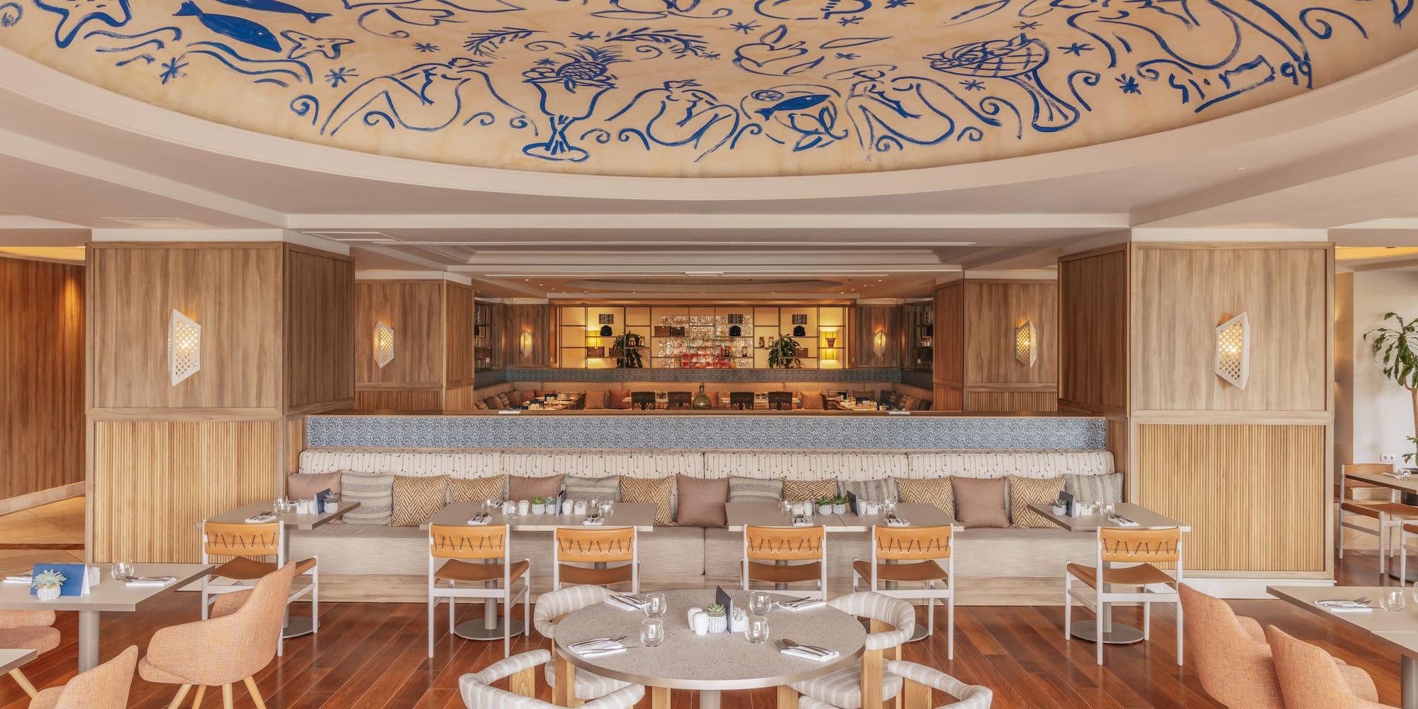 Restaurant dining area with blue abstract ceiling art and warm wooden interior.