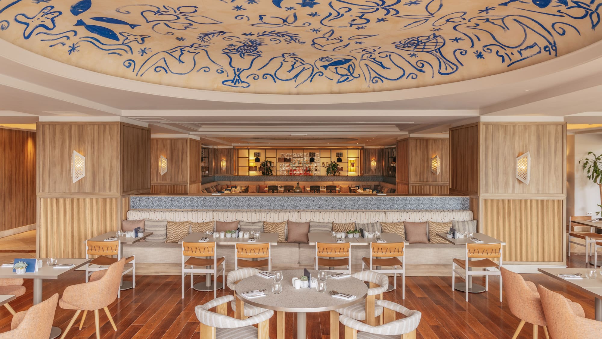 Restaurant dining area with blue abstract ceiling art and warm wooden interior.