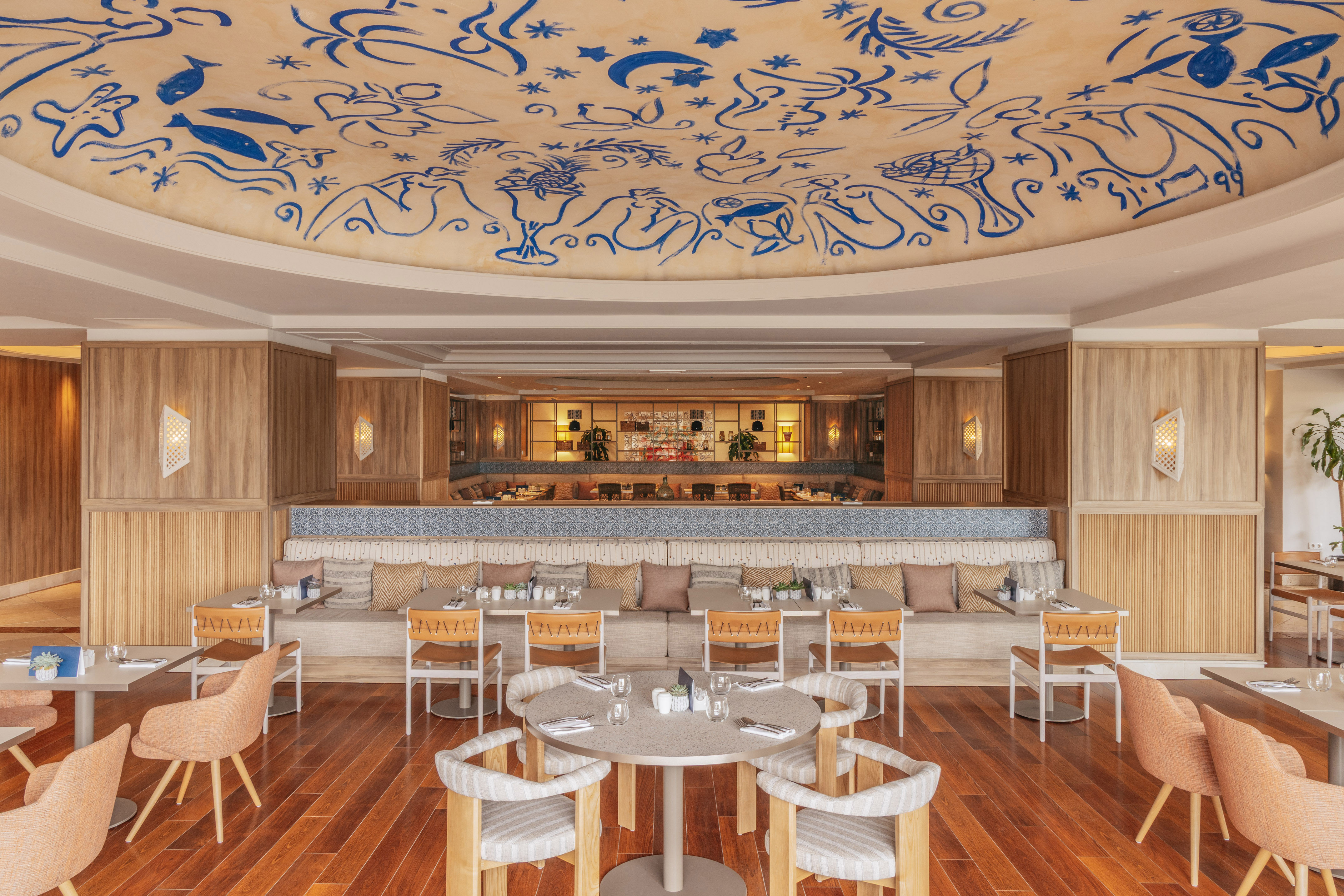 Restaurant dining area with blue abstract ceiling art and warm wooden interior.