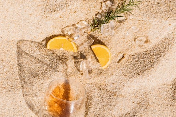 a glass of wine and ice cubes on sand