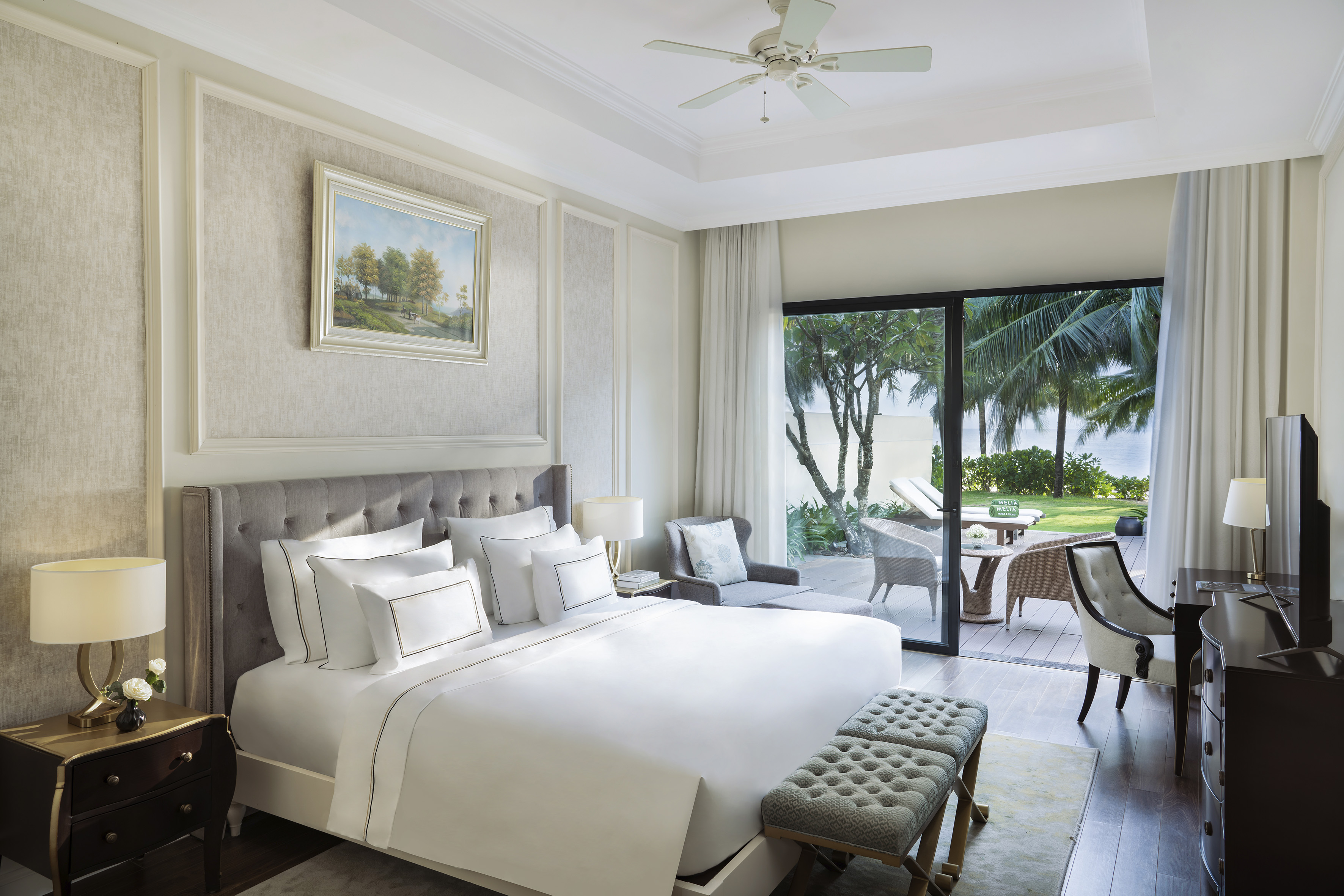 Luxury bedroom with king bed, ocean view, private terrace, and tropical garden.