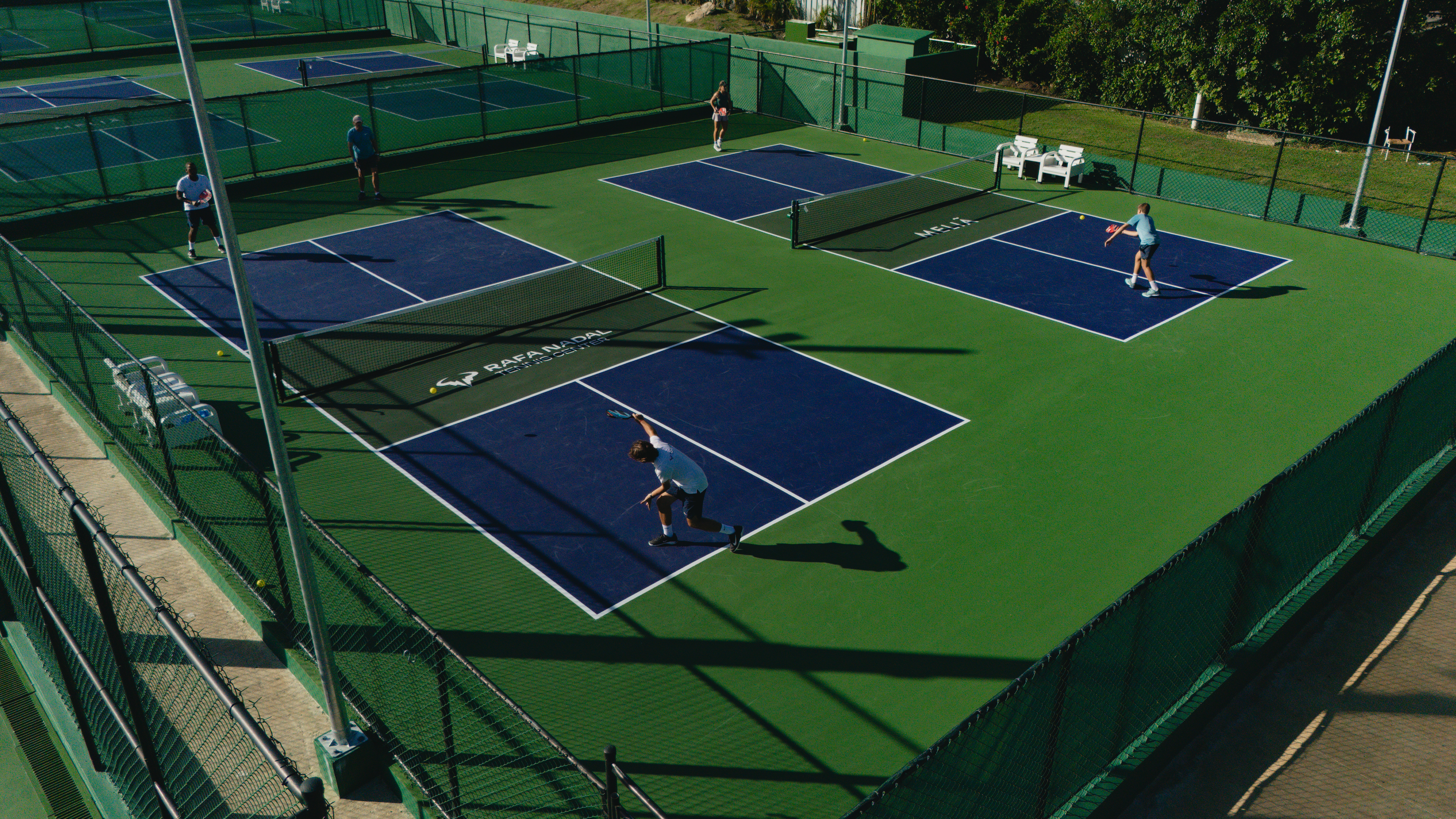 People playing on green and blue Rafa Nadal Meliá pickleball courts.