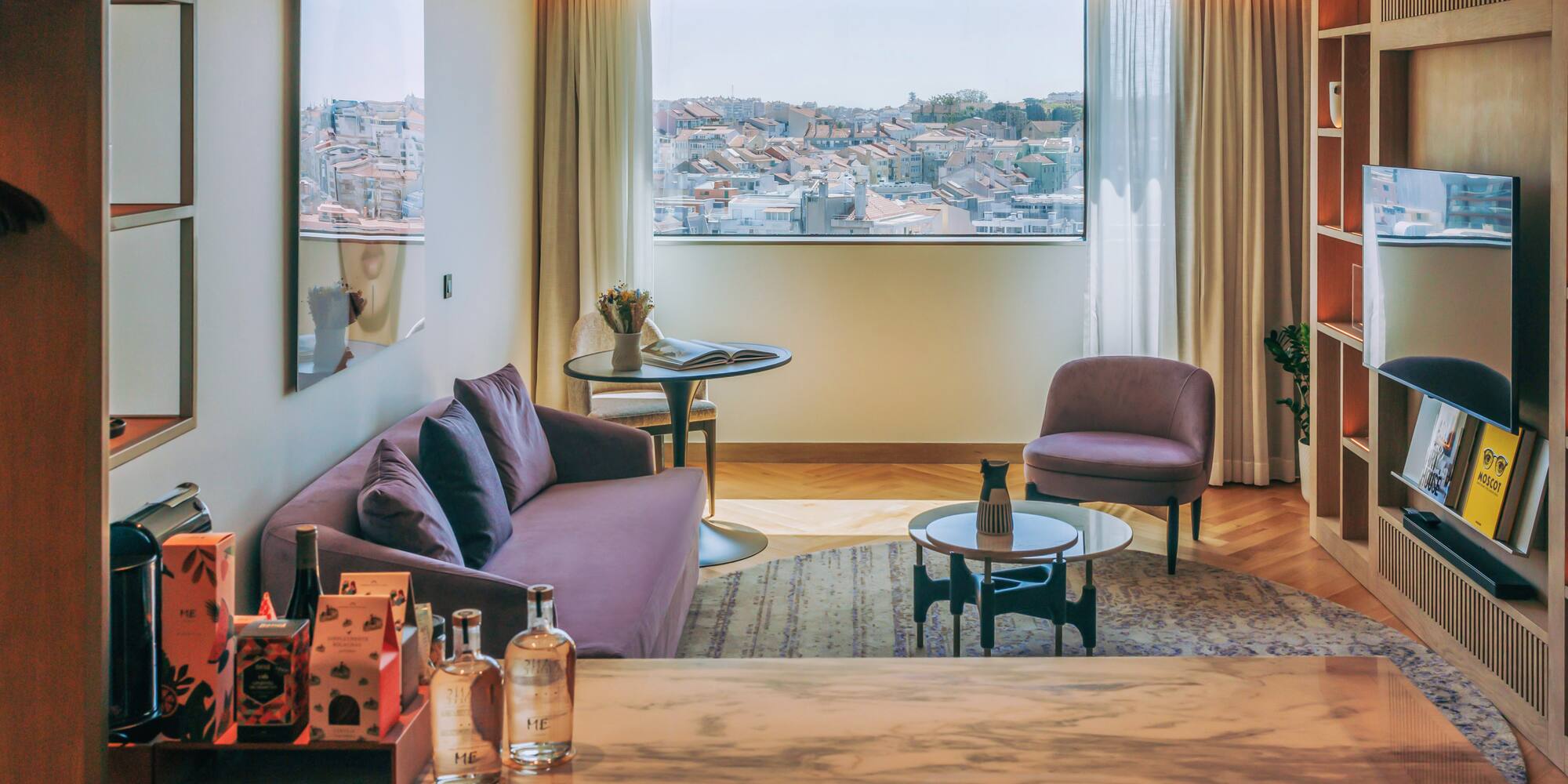 Elegant hotel living room with purple sofa, city rooftop view, and marble counter.