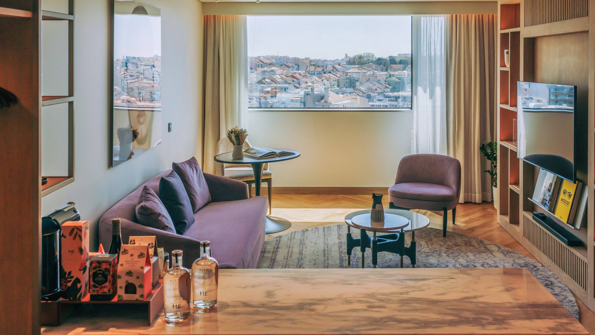 Elegant hotel living room with purple sofa, city rooftop view, and marble counter.