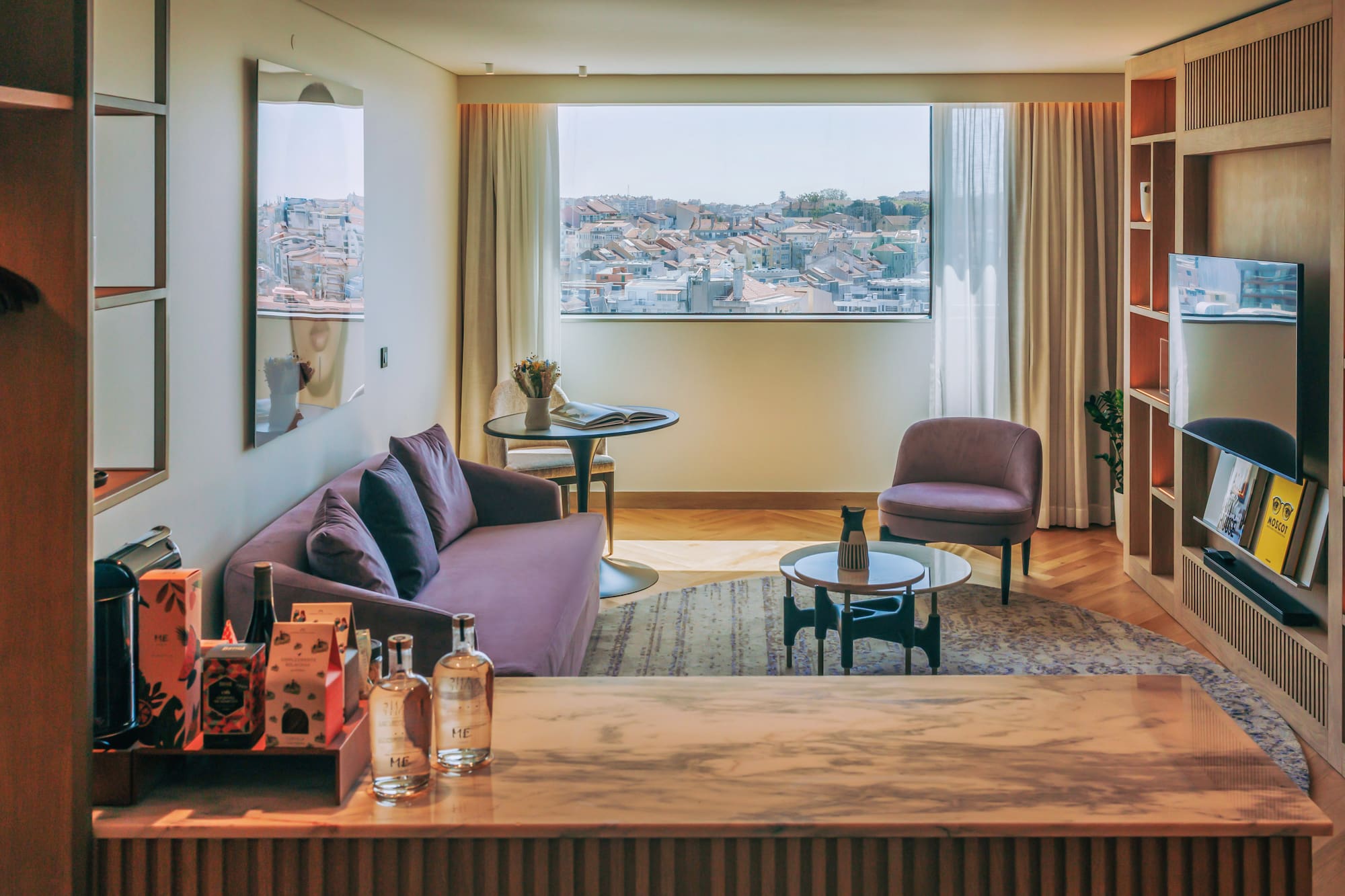 Elegant hotel living room with purple sofa, city rooftop view, and marble counter.