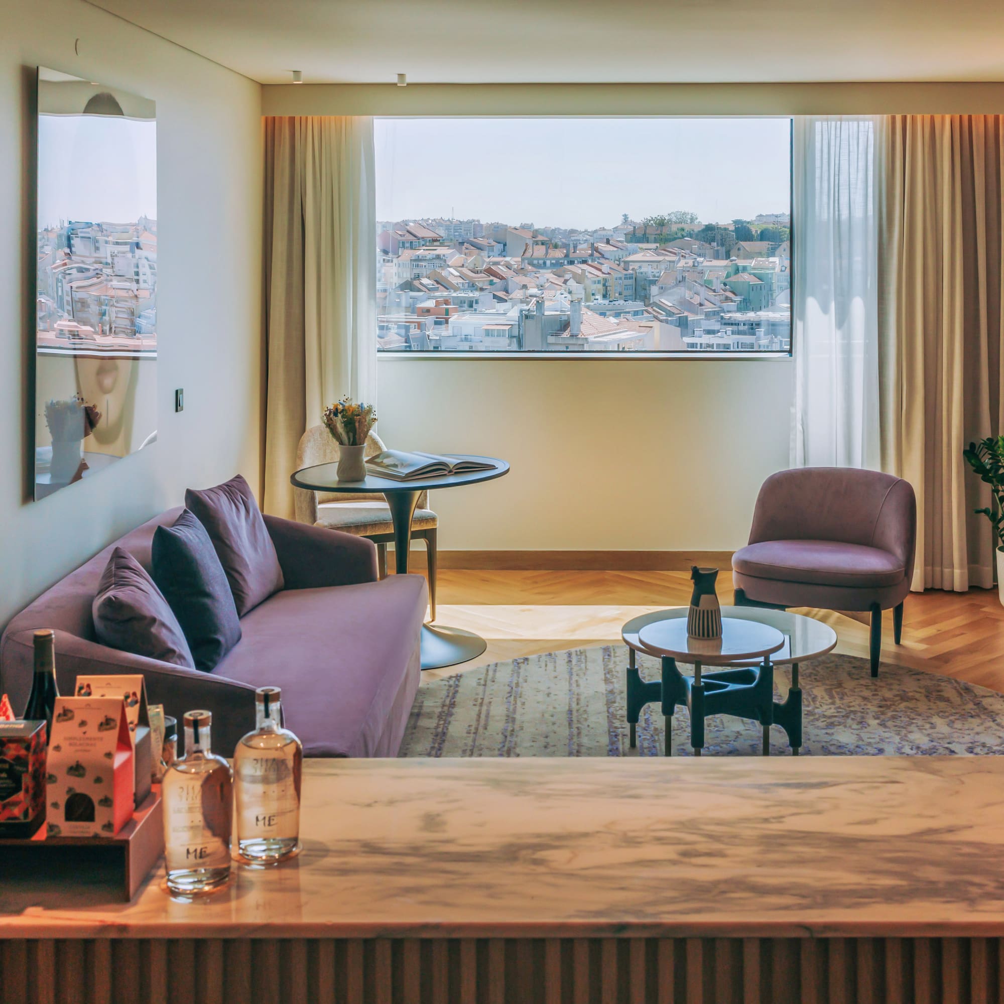 Elegant hotel living room with purple sofa, city rooftop view, and marble counter.