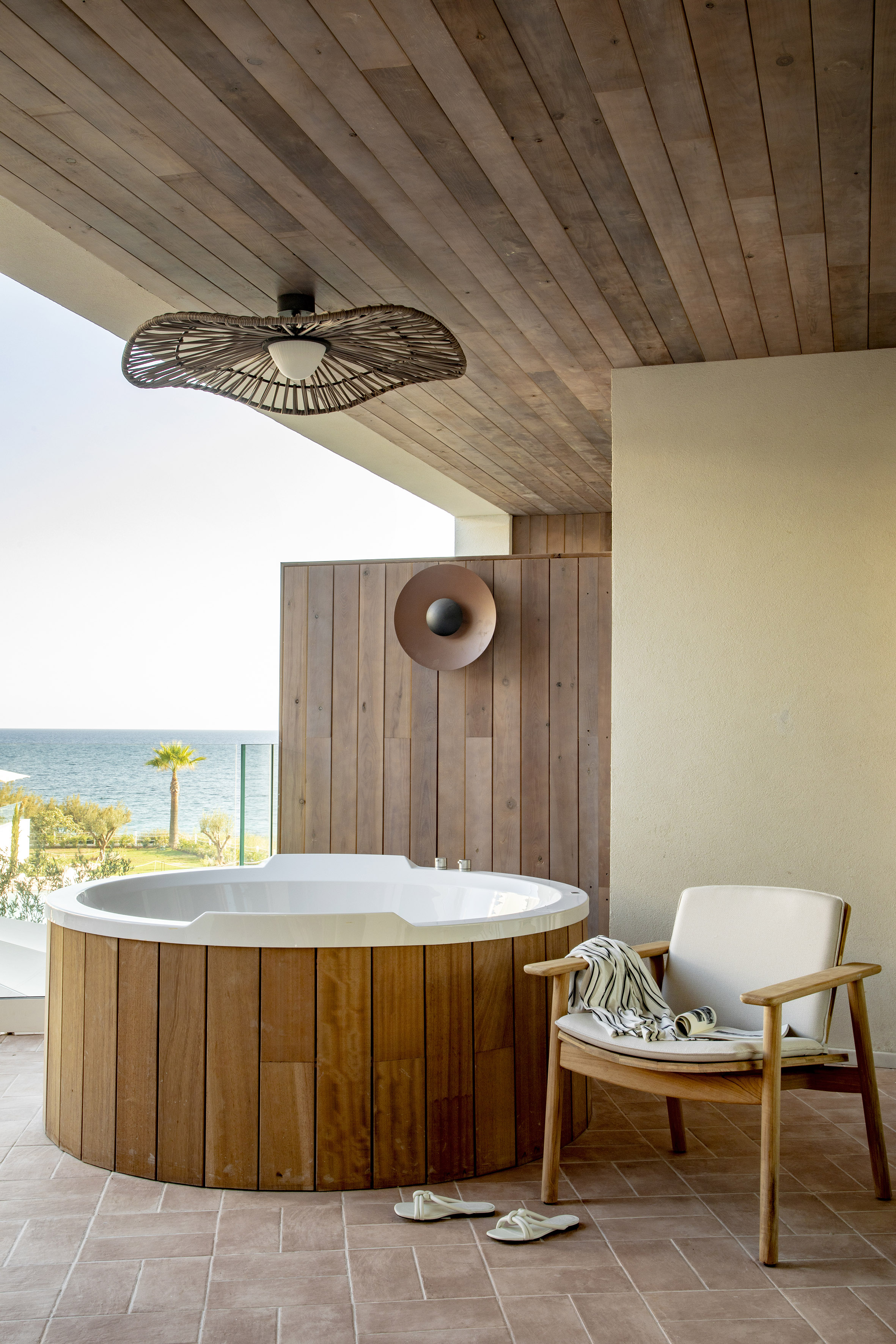 Balcony with outdoor hot tub, sea view, wooden features, and lounge chair.
