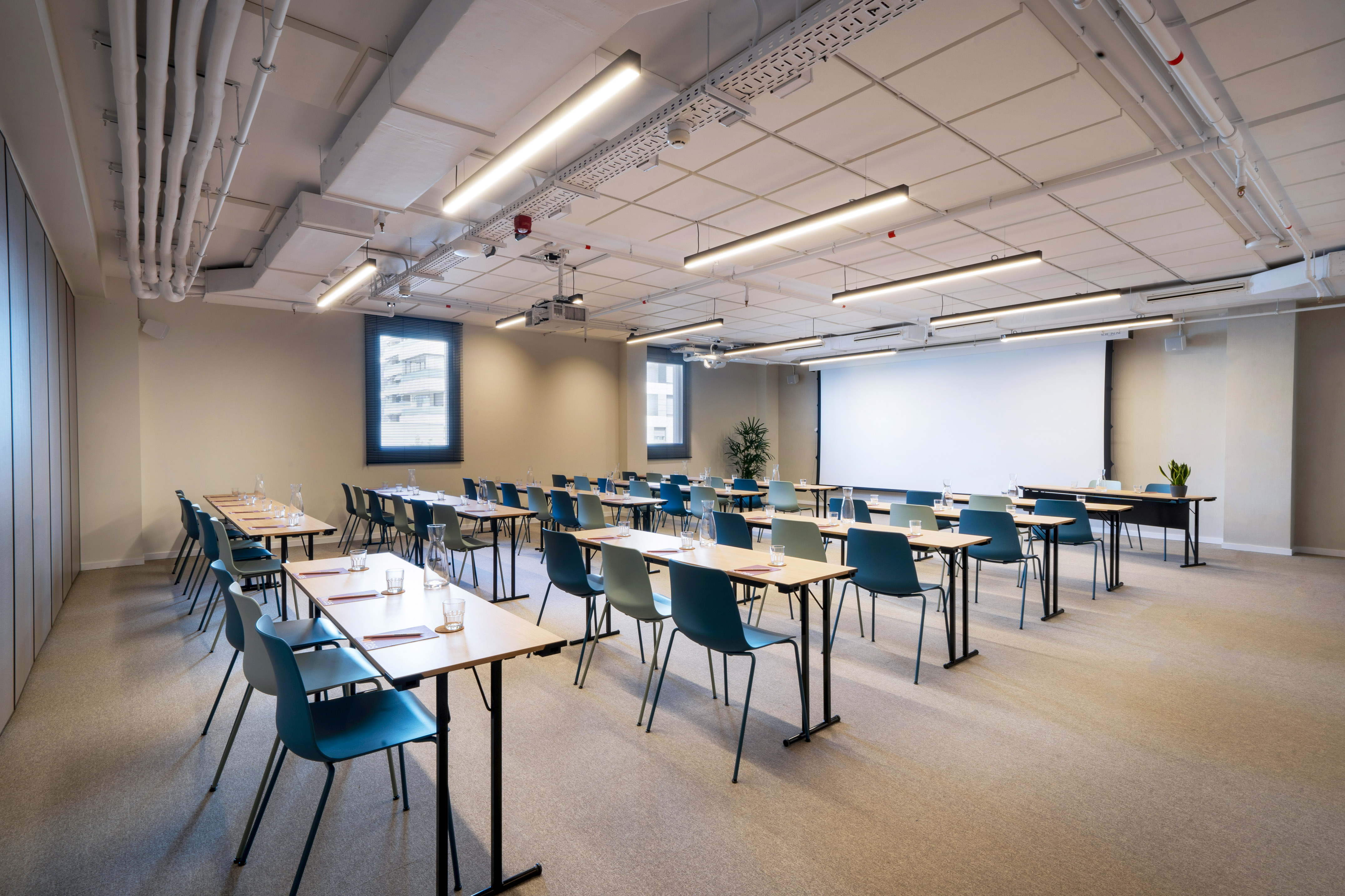 Empty modern meeting room with classroom tables, chairs, and projector screen.