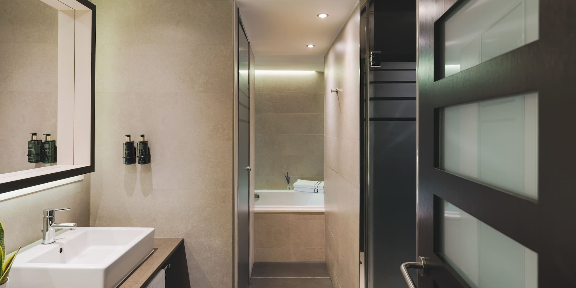 Baño moderno con lavabo doble, diseño contemporáneo y acceso a ducha/bañera.