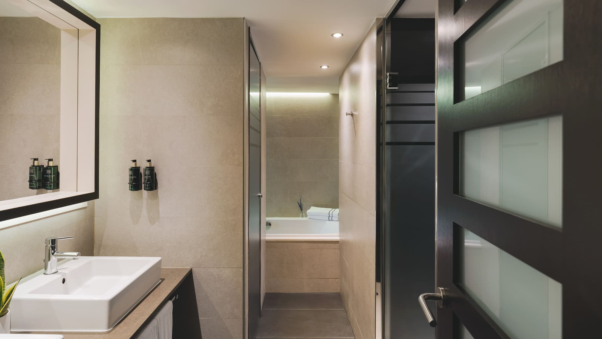 Baño moderno con lavabo doble, diseño contemporáneo y acceso a ducha/bañera.