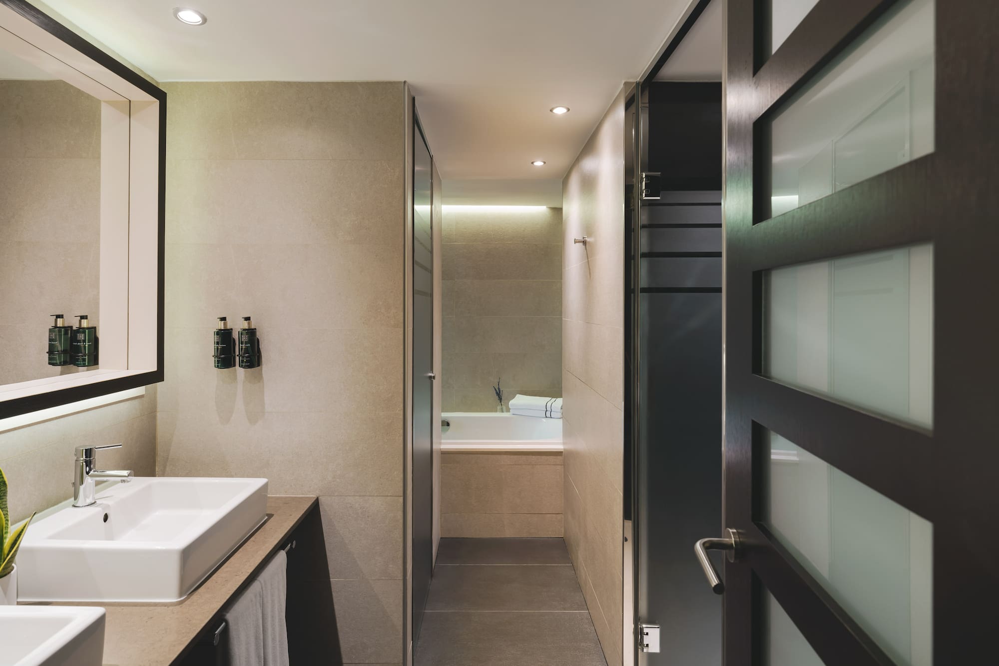 Baño moderno con lavabo doble, diseño contemporáneo y acceso a ducha/bañera.