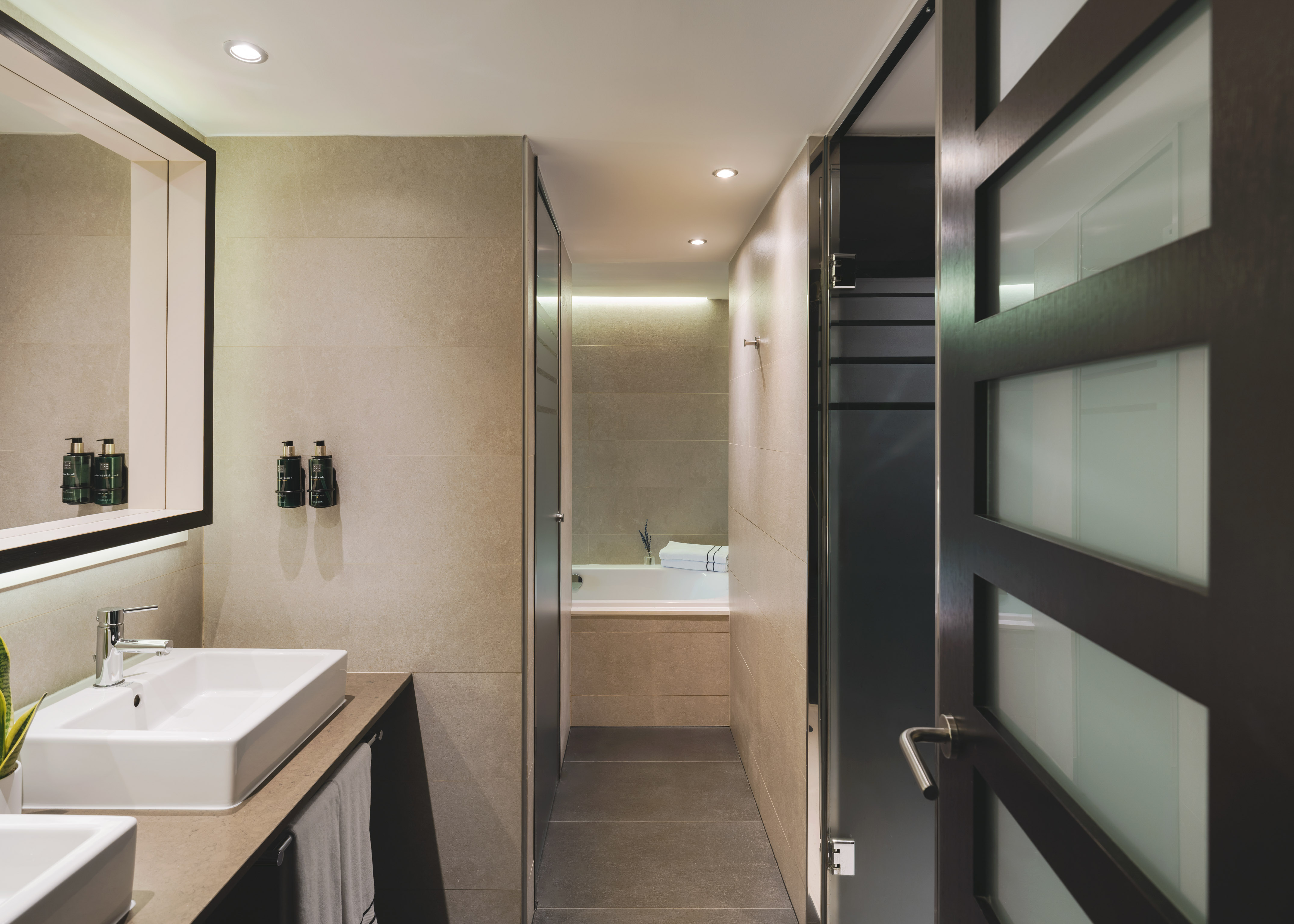 Baño moderno con lavabo doble, diseño contemporáneo y acceso a ducha/bañera.