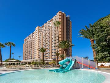 a pool with a slide and palm trees in front of a building