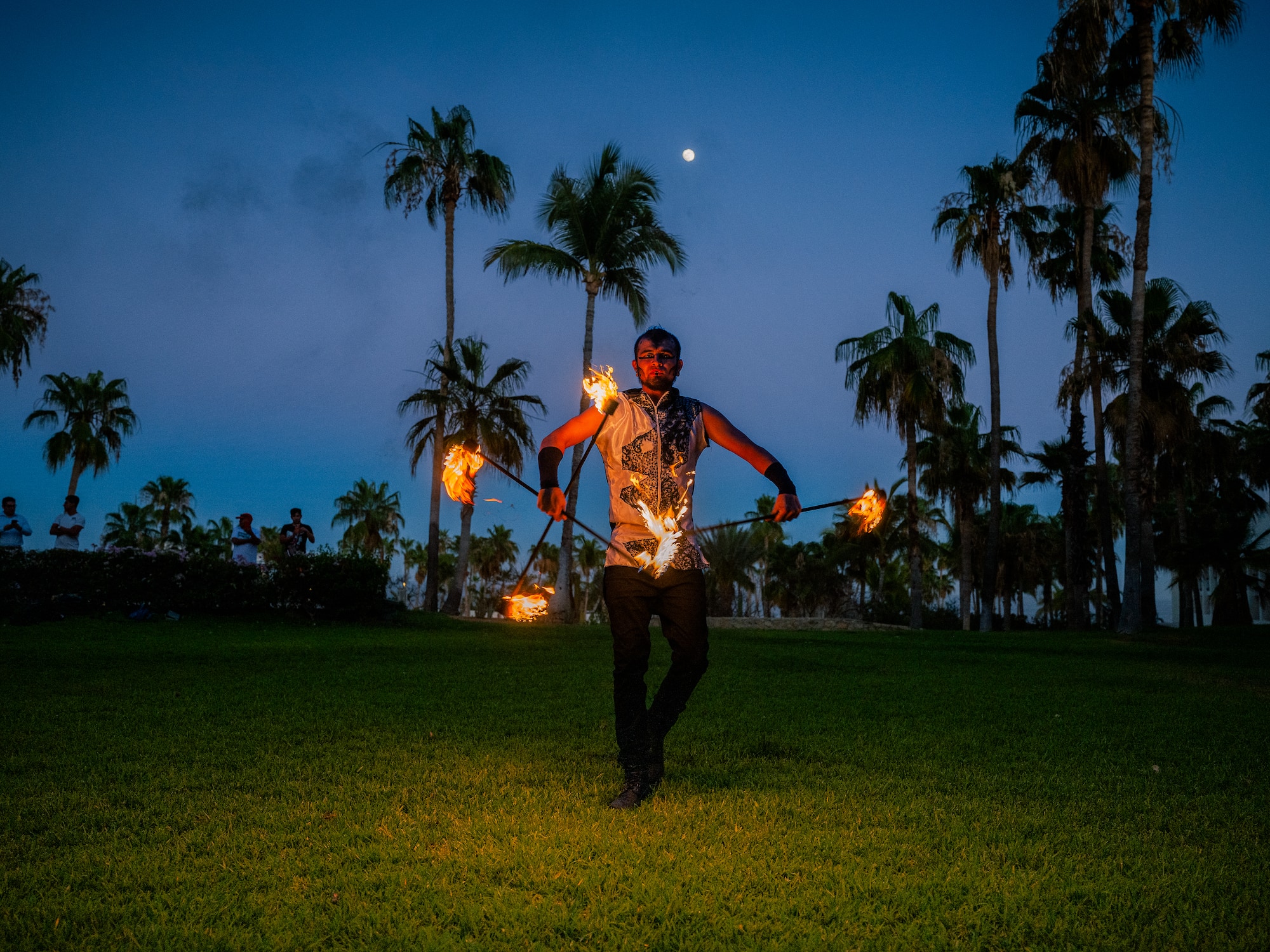 a man with fire on sticks in a grass field