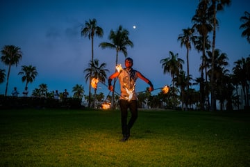a man with fire on sticks in a grass field