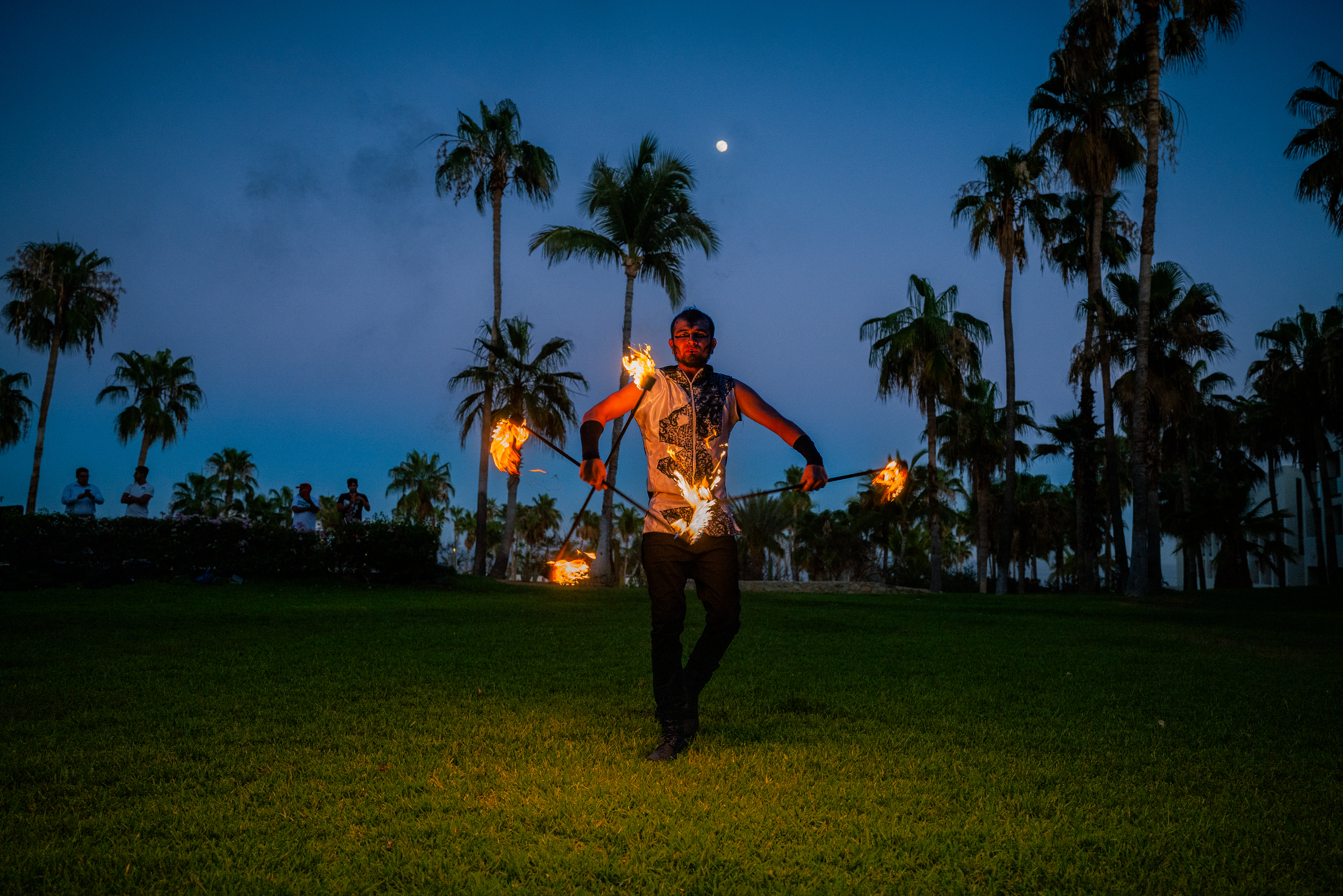 a man with fire on sticks in a grass field
