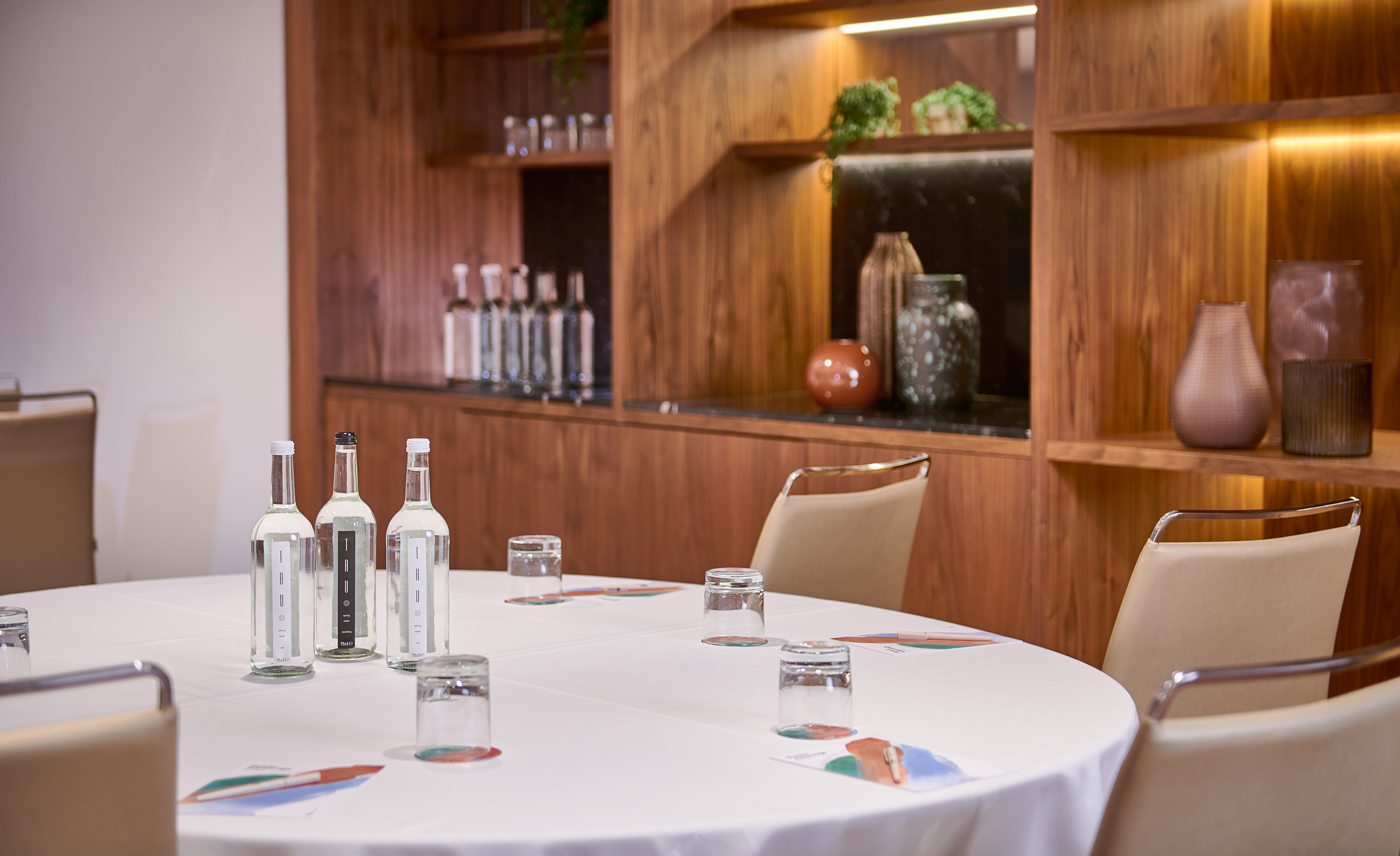 Professional meeting setup with round table, water, and wooden decor.