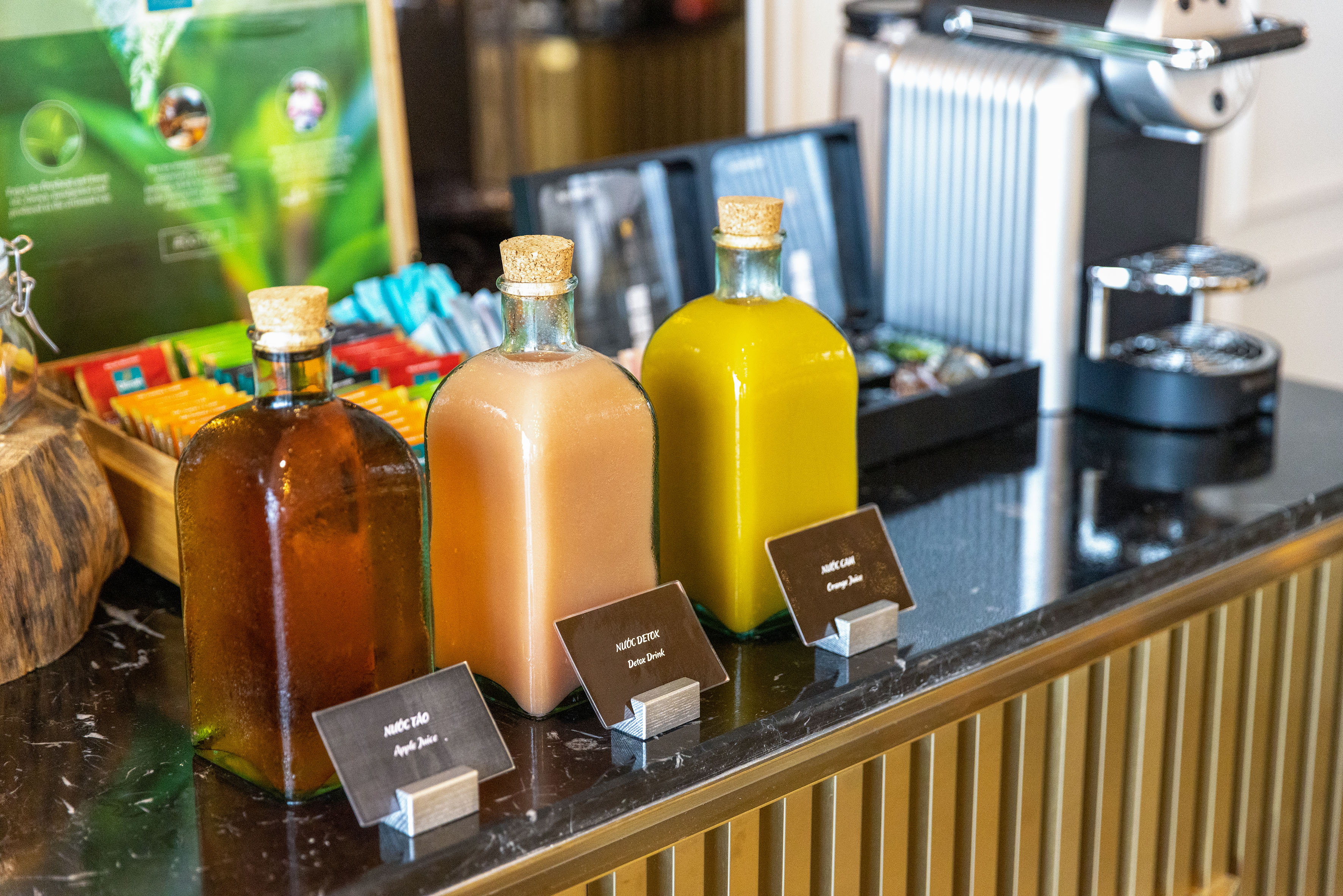 Bottled apple, detox, and orange juices on a hotel breakfast buffet.