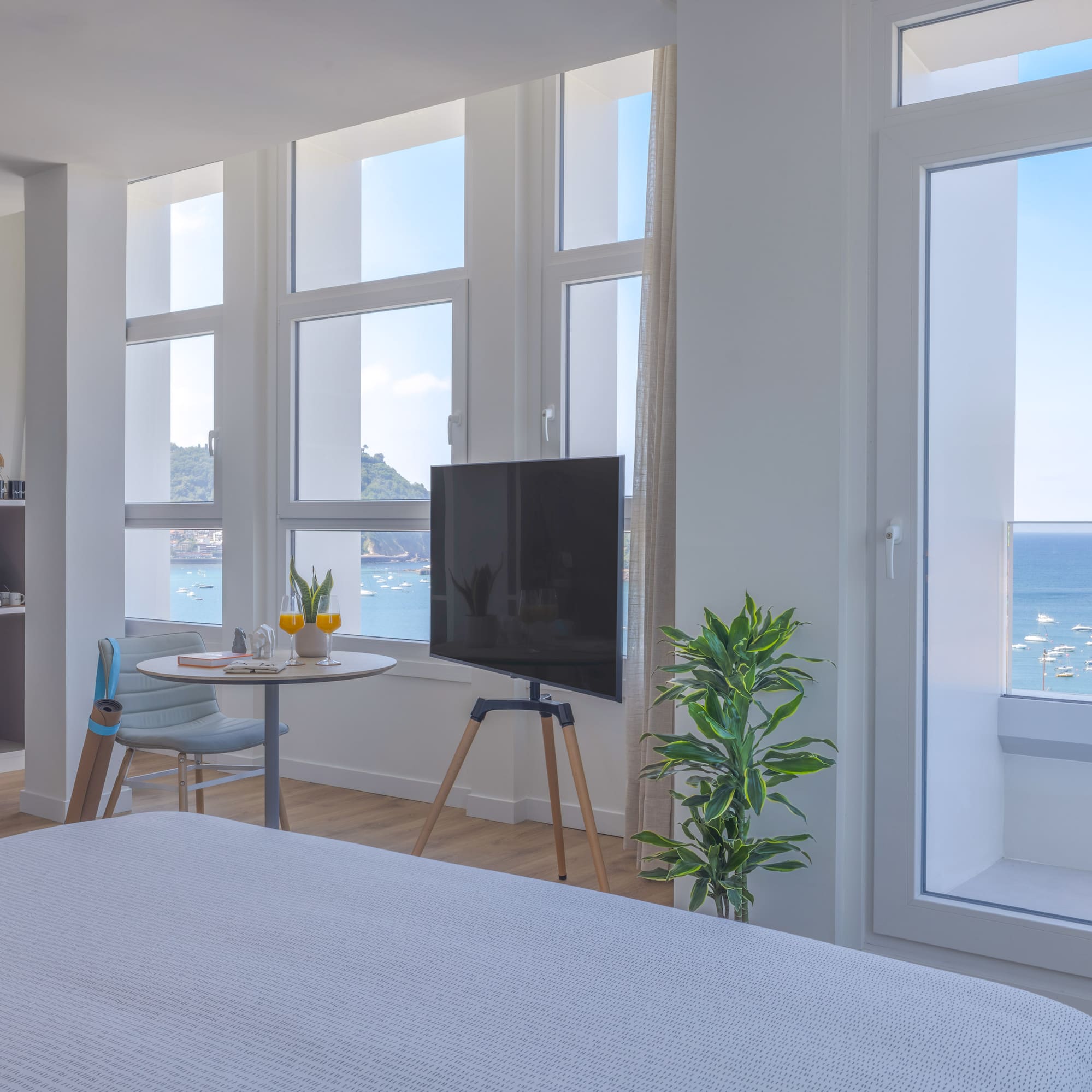 Moderna habitación de hotel con vistas al mar y bahía, barcos y TV.