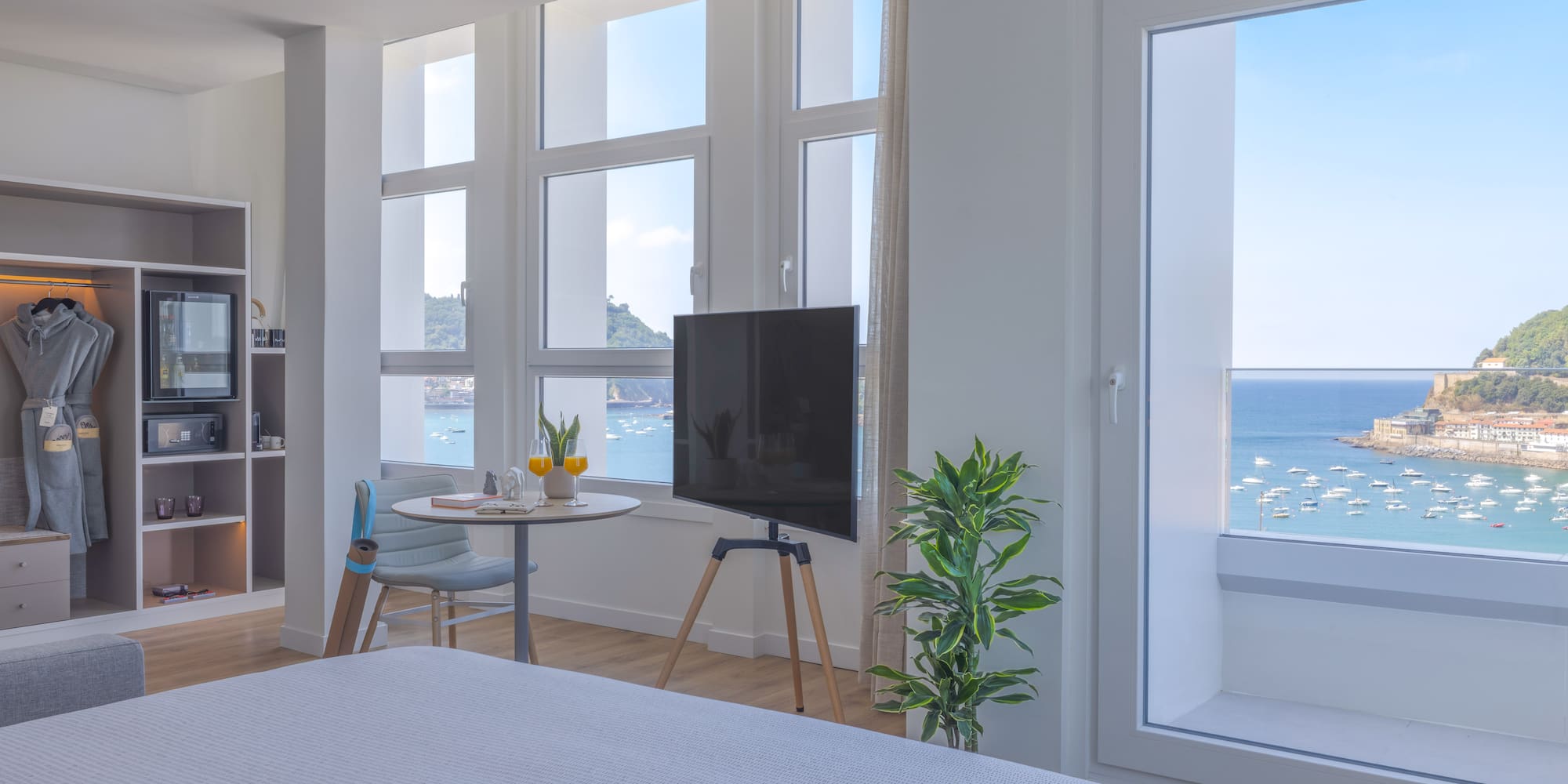 Moderna habitación de hotel con vistas al mar y bahía, barcos y TV.