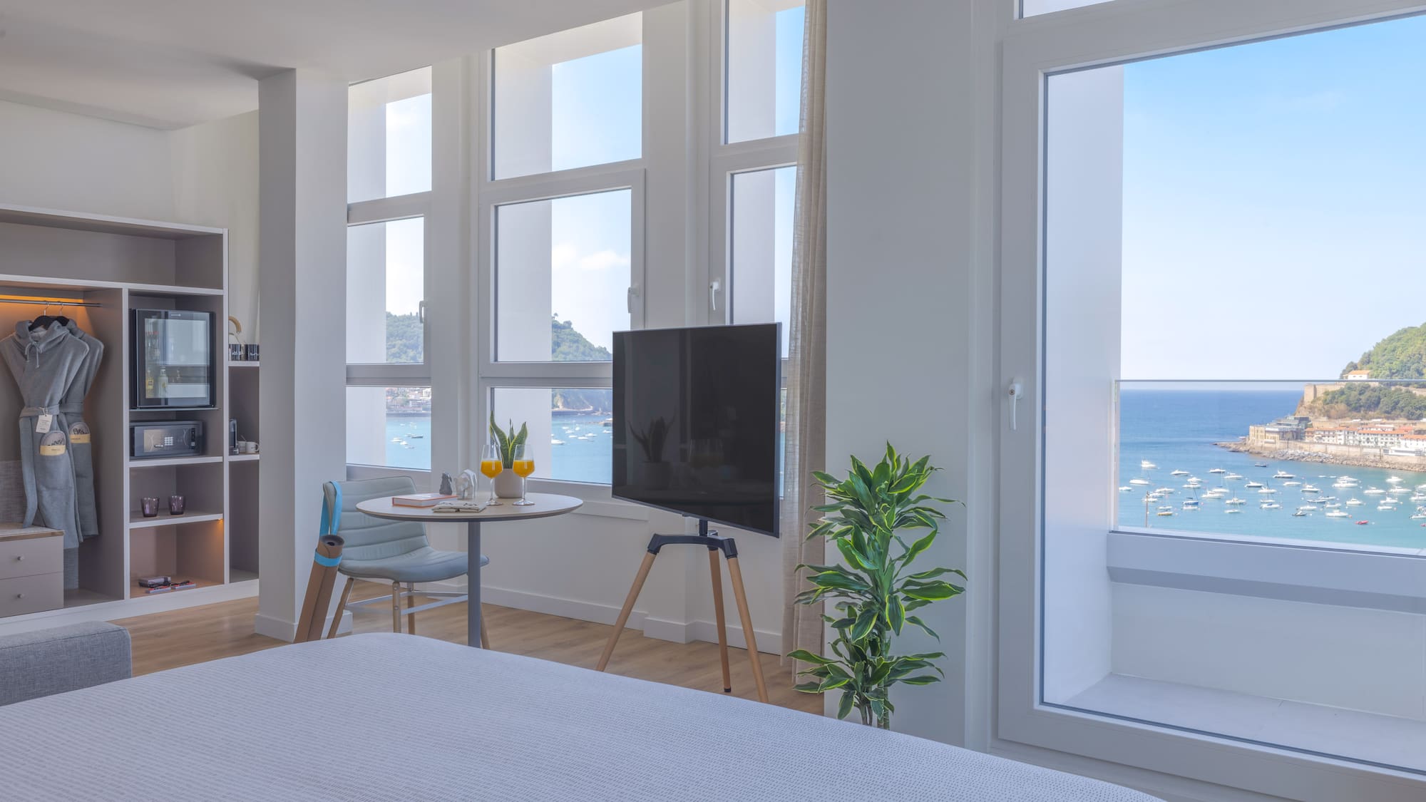 Moderna habitación de hotel con vistas al mar y bahía, barcos y TV.