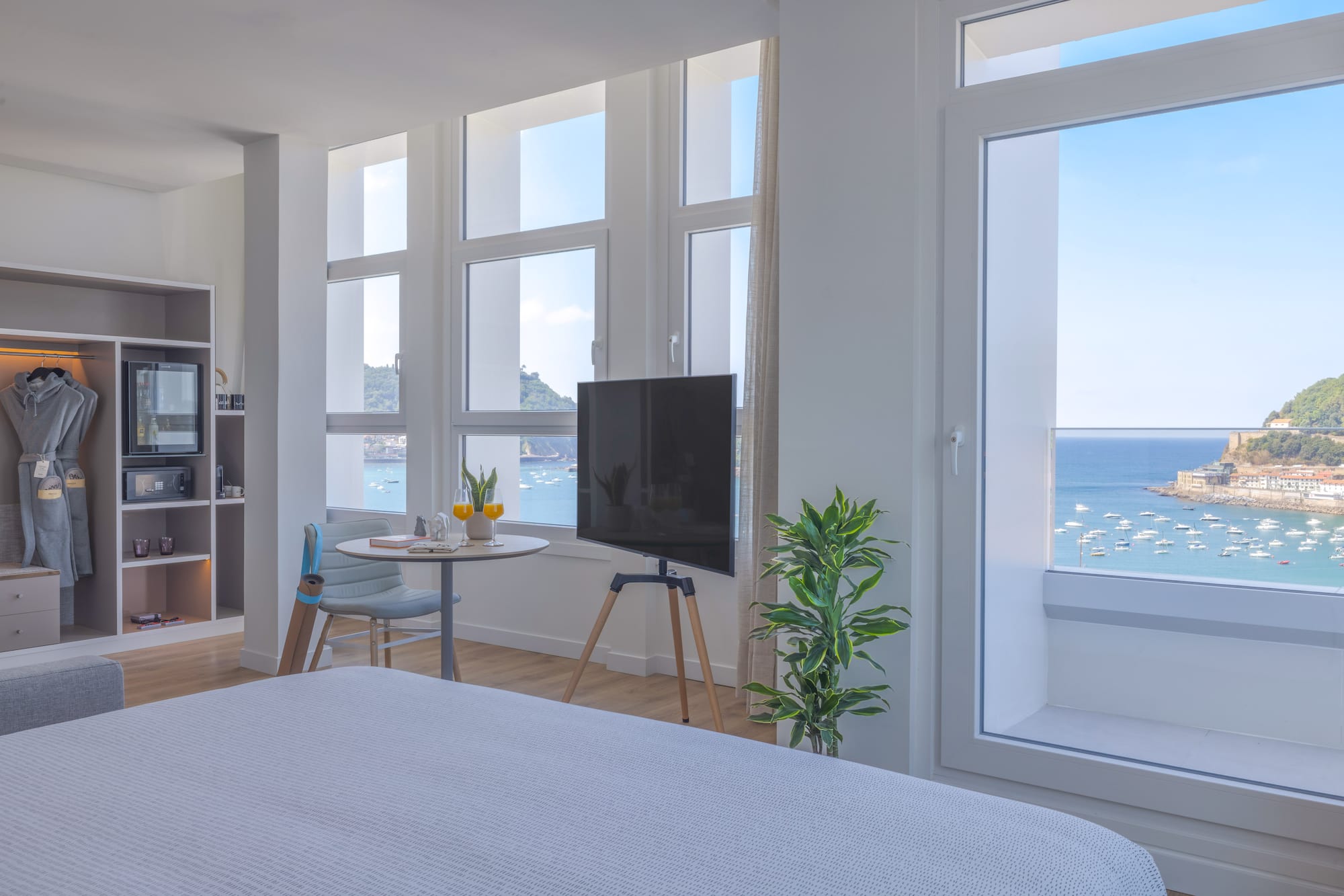 Moderna habitación de hotel con vistas al mar y bahía, barcos y TV.