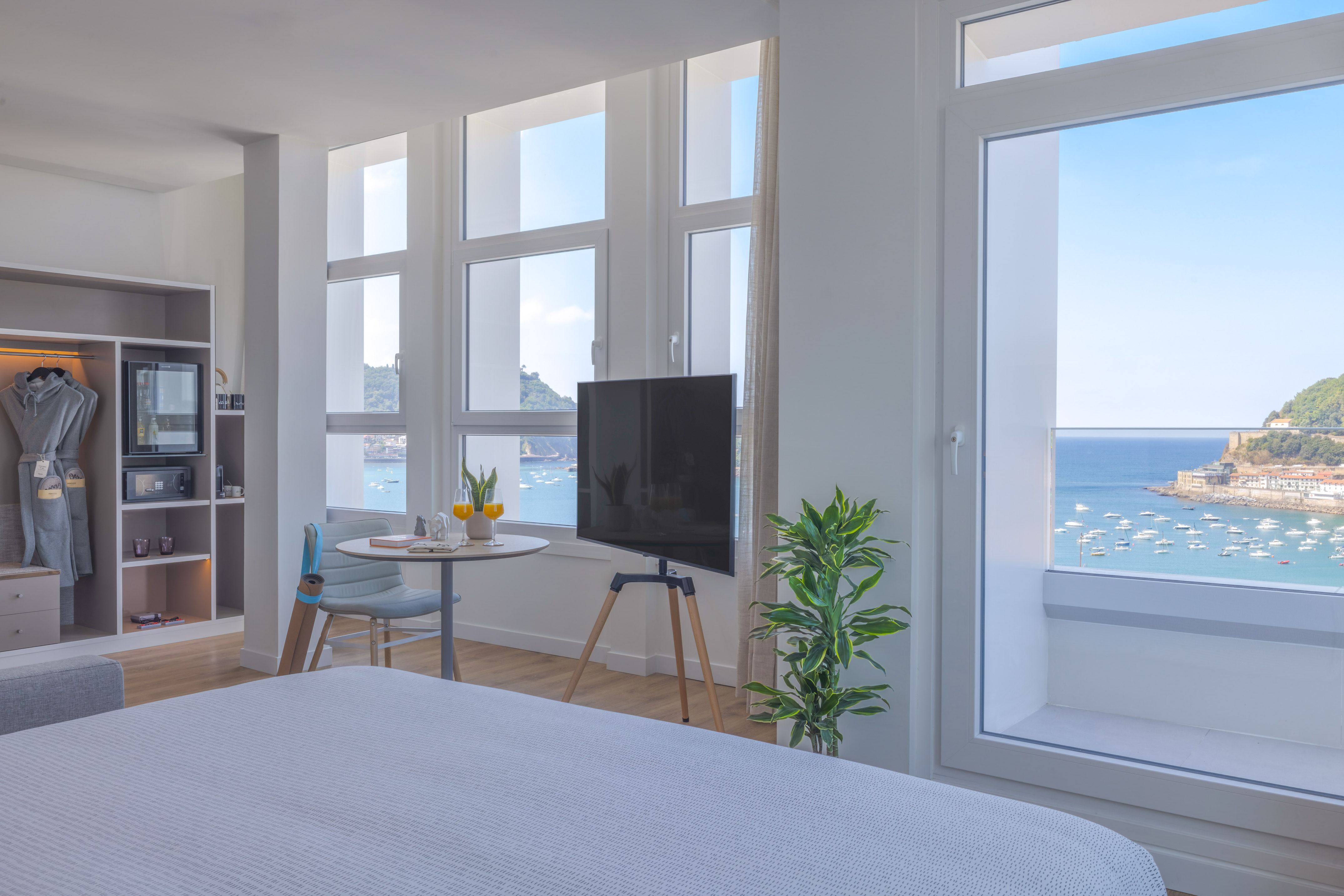 Moderna habitación de hotel con vistas al mar y bahía, barcos y TV.