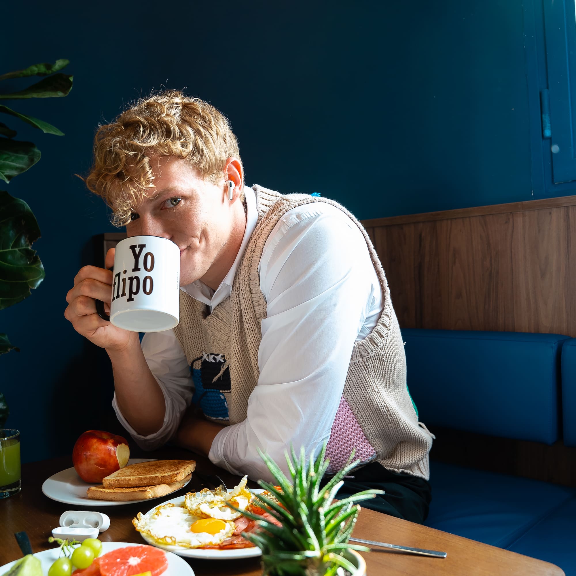 A man sits at a table with a cup of coffee and some food.