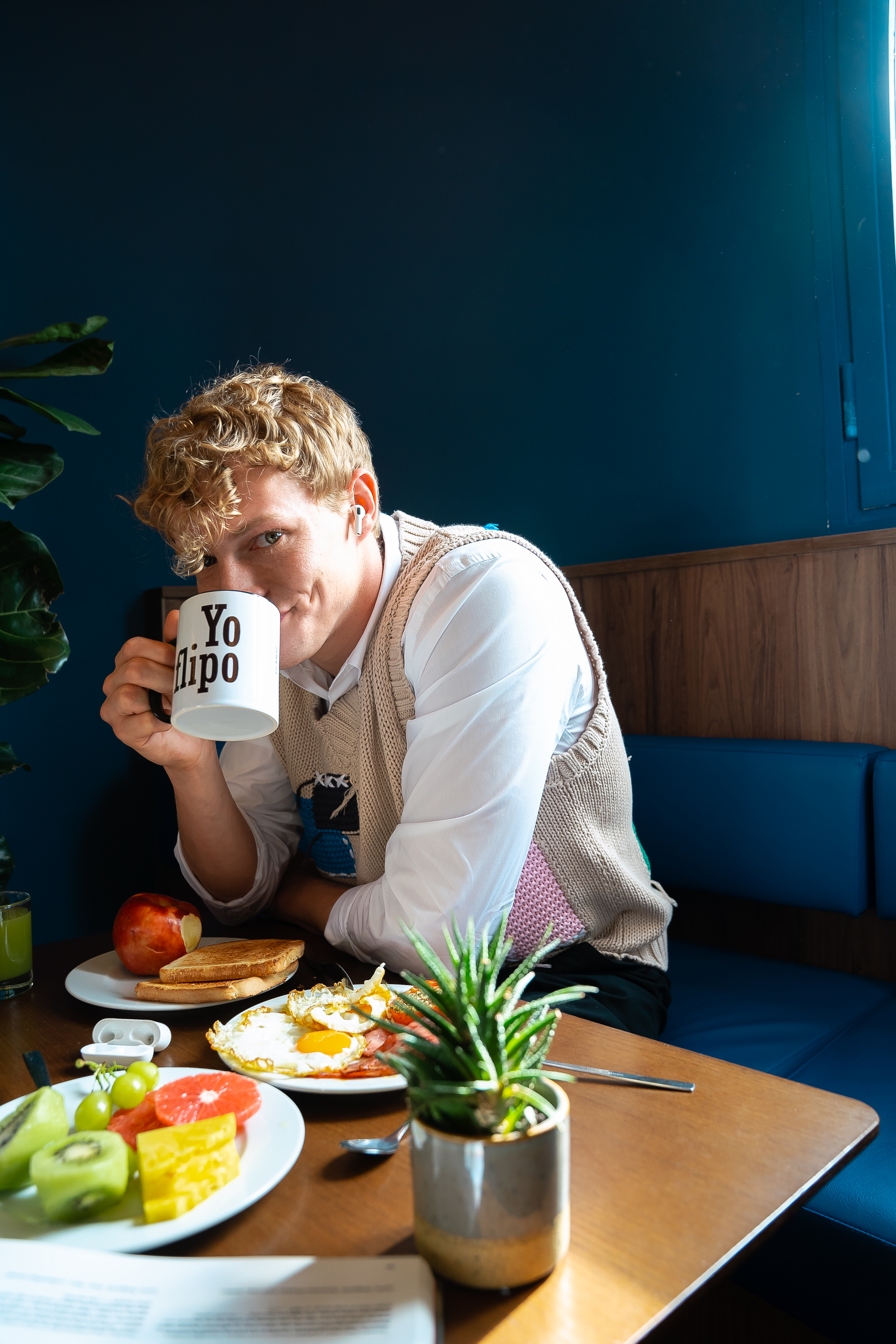 A man sits at a table with a cup of coffee and some food.