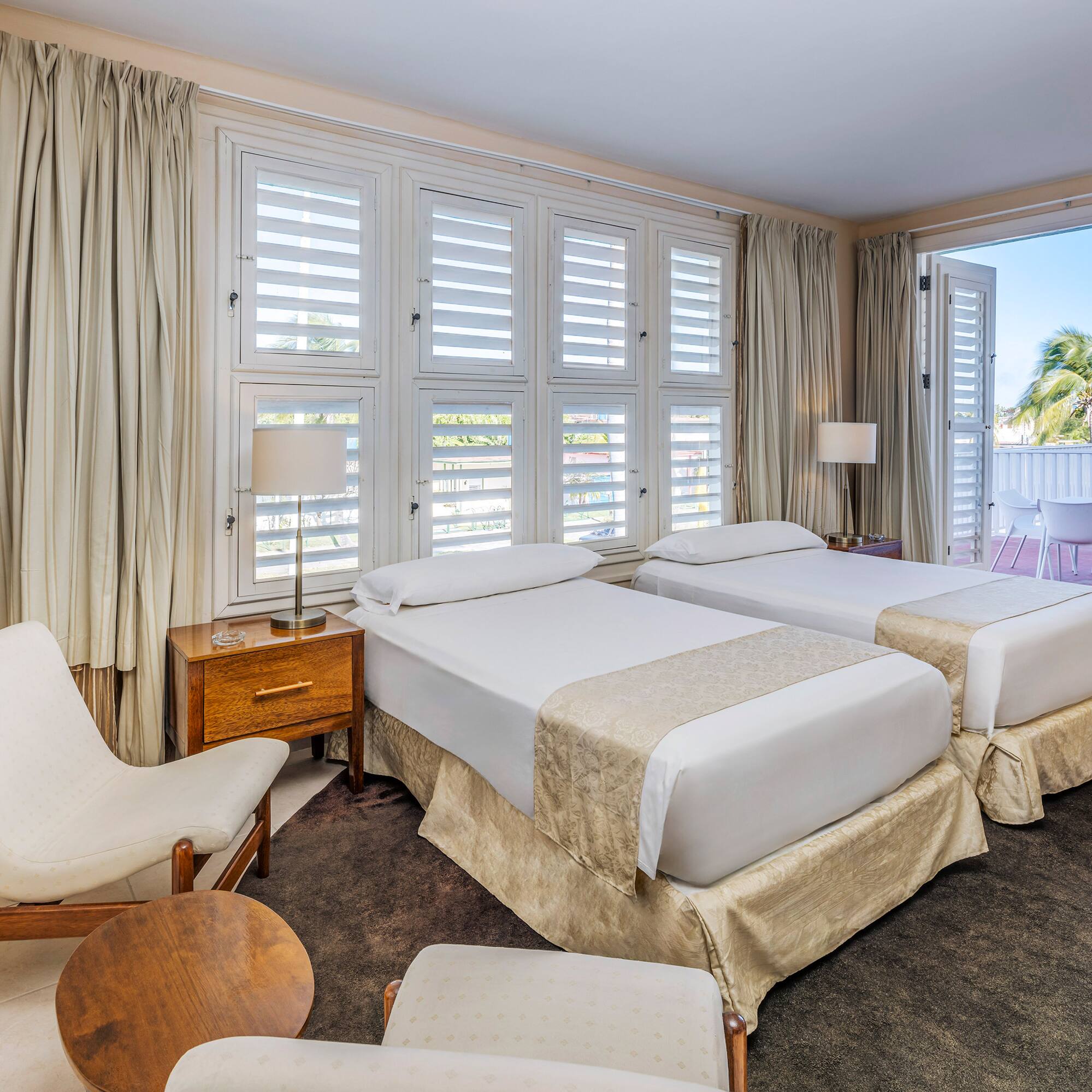 a room with two beds and chairs