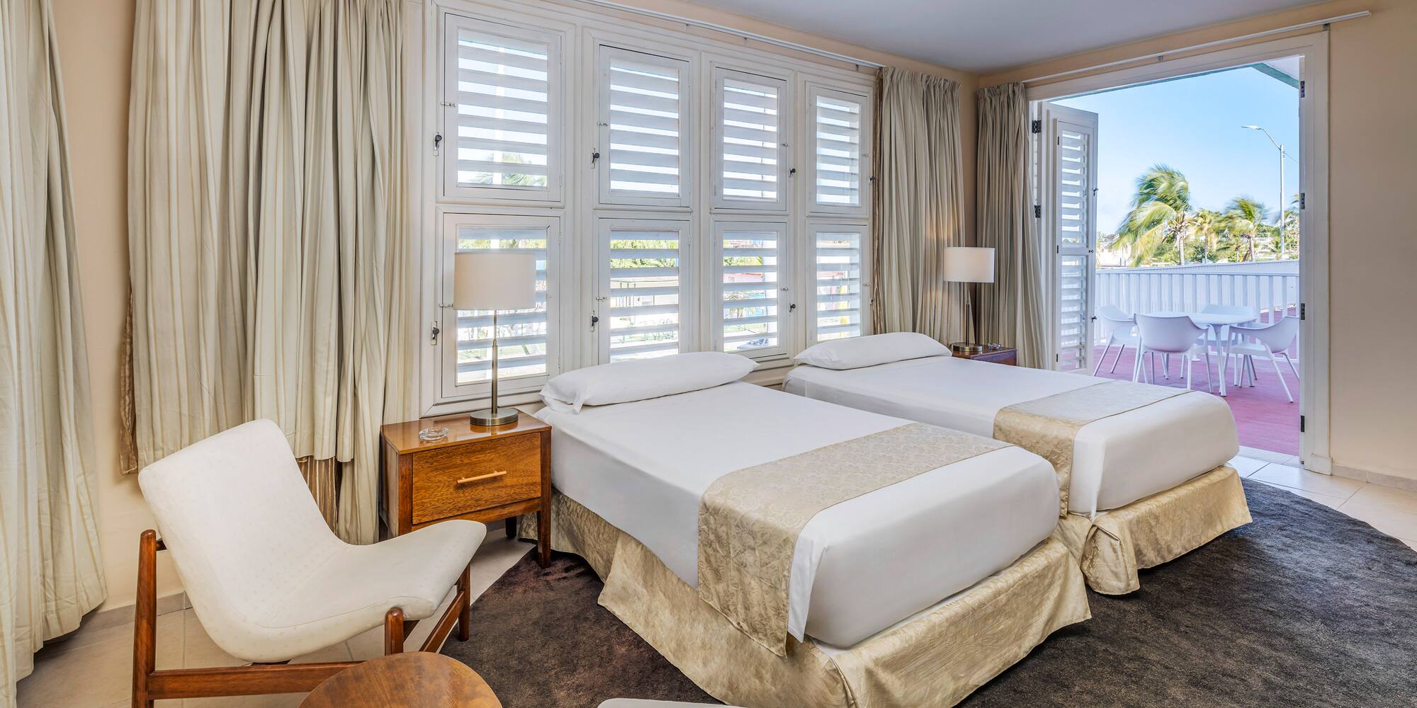 a room with two beds and chairs