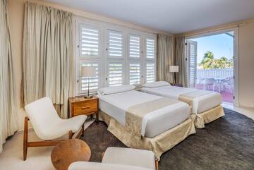 a room with two beds and chairs