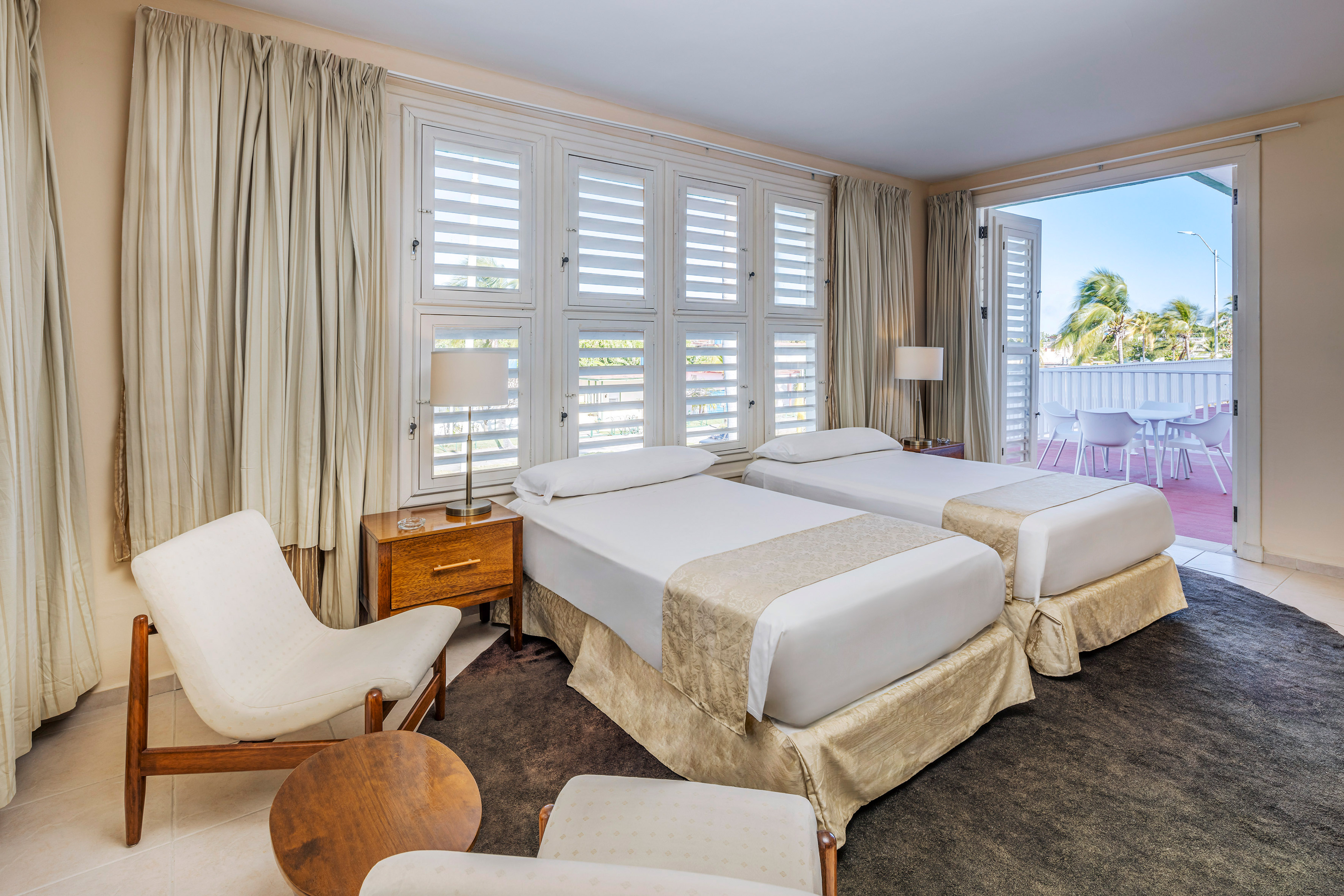 a room with two beds and chairs