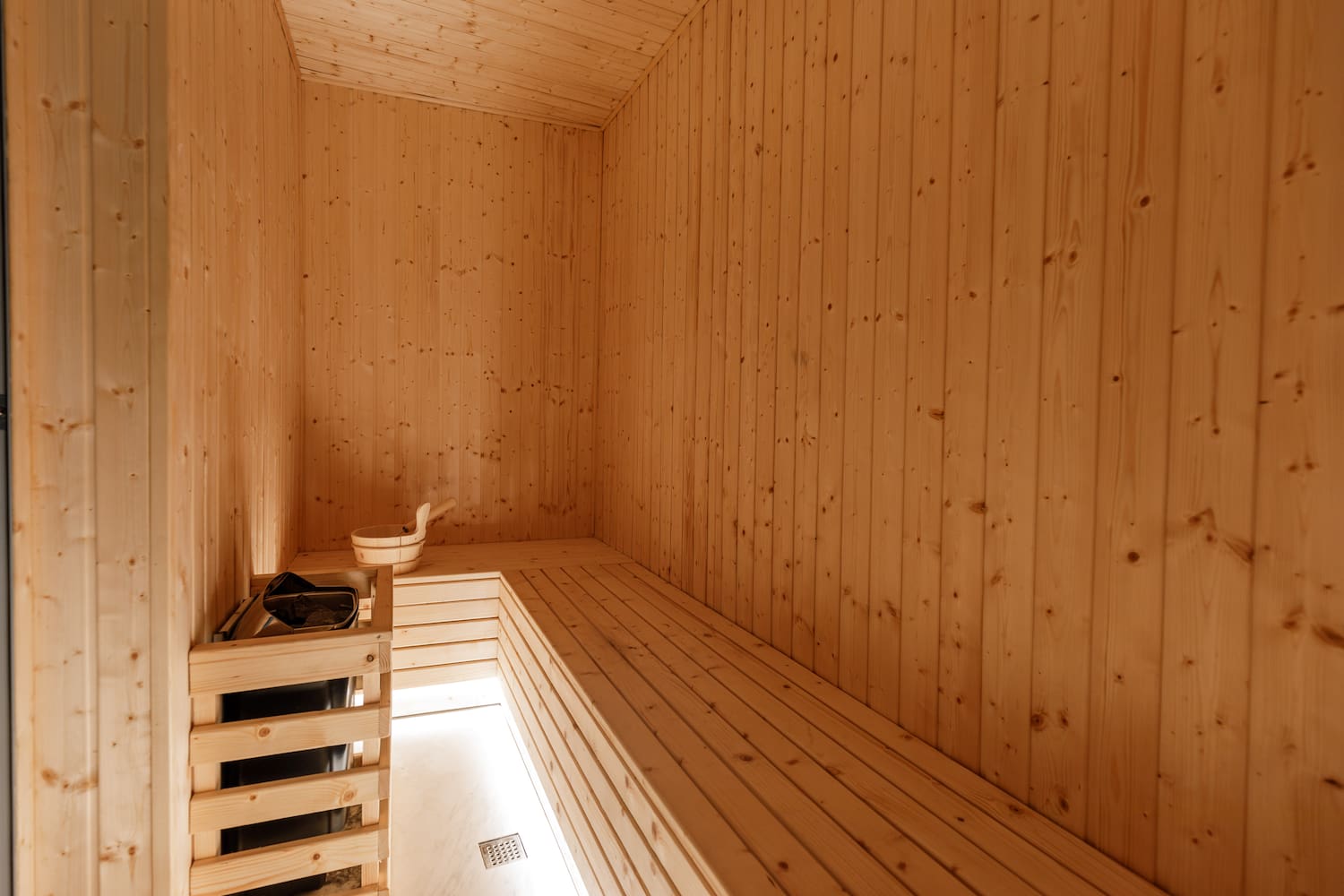 a wooden room with a bench and a bucket