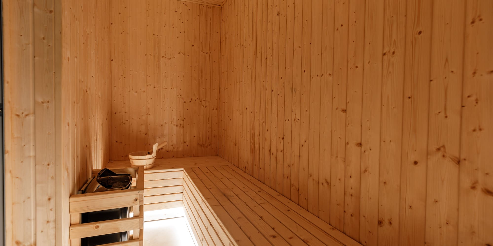 a wooden room with a bench and a bucket