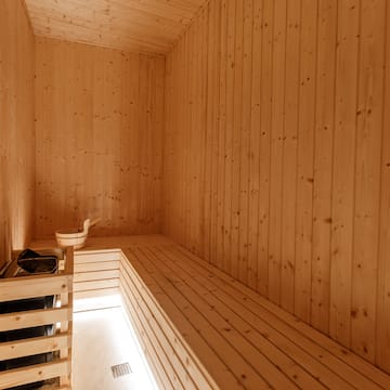 a wooden room with a bench and a bucket