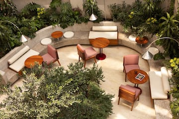 Outdoor patio with modern furniture, concrete seating, and lush tropical plants.
