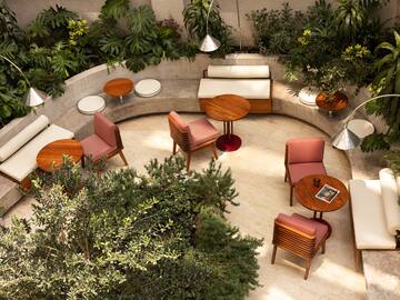 Modern outdoor lounge with wooden furniture, striped chairs, and tropical plants.
