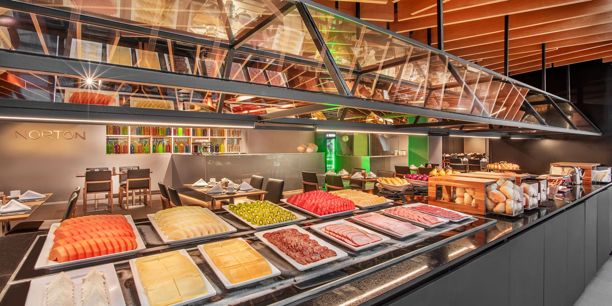 Modern hotel buffet featuring fresh fruit, cheeses, charcuterie, and bread.
