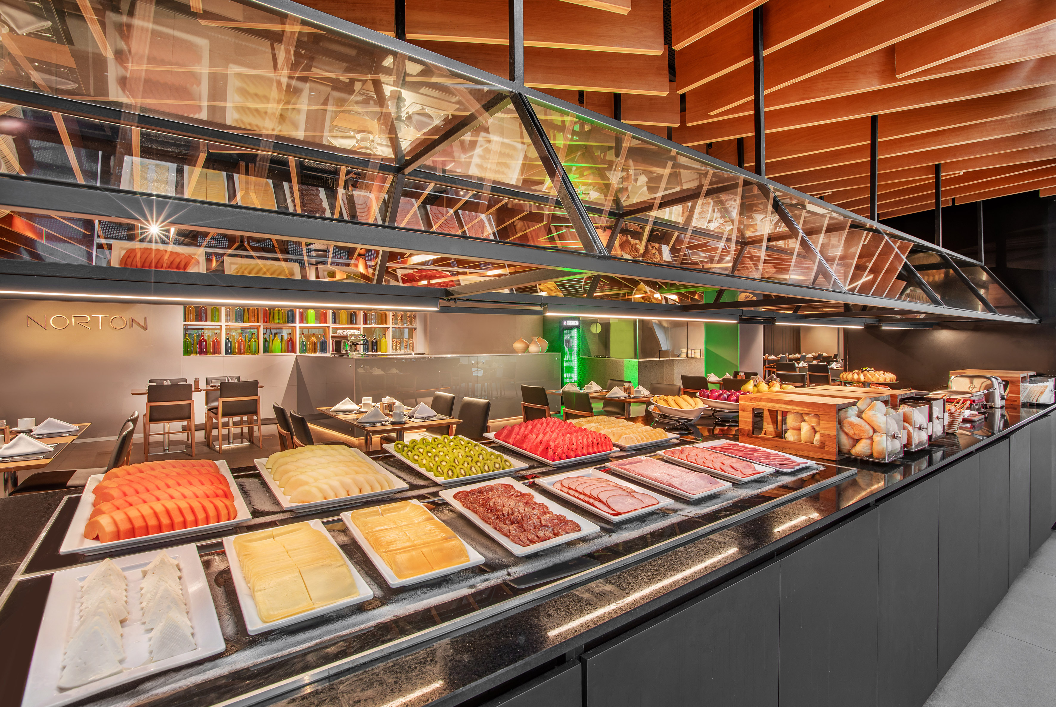 Modern hotel buffet featuring fresh fruit, cheeses, charcuterie, and bread.