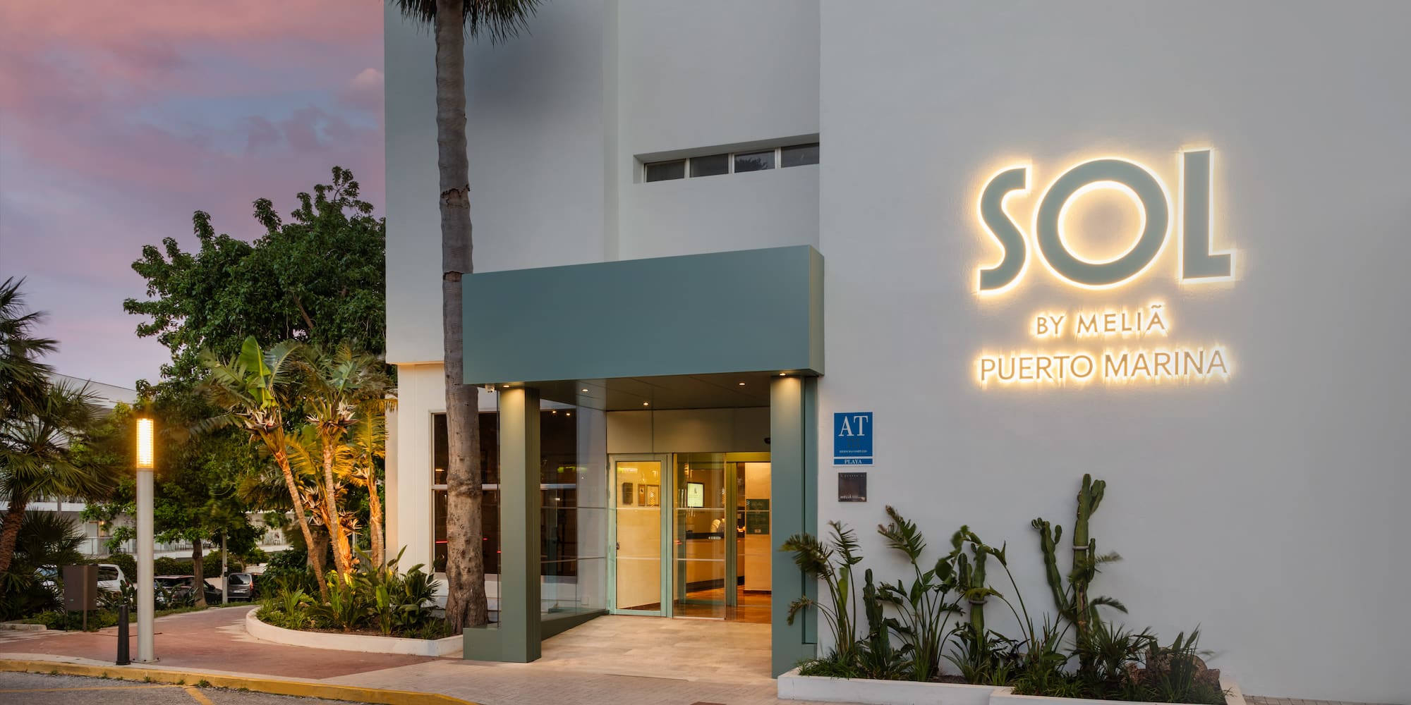 Sol by Meliá Puerto Marina hotel exterior, illuminated sign at dusk.